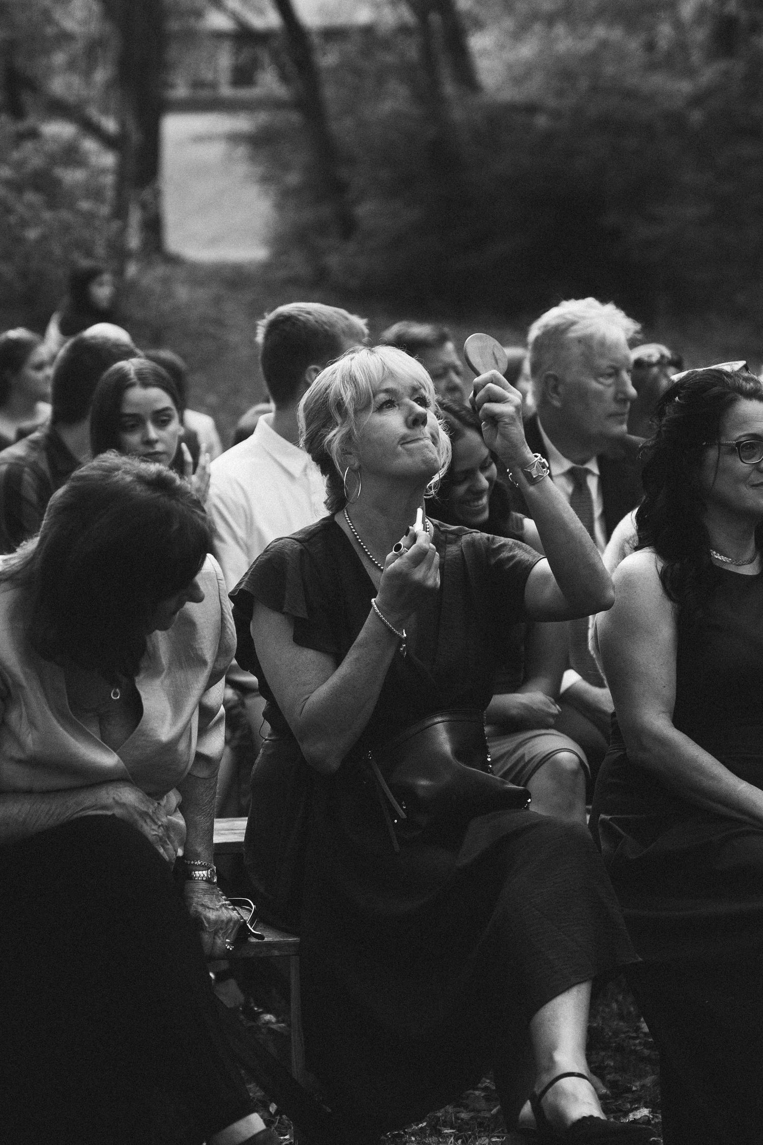 Black and white photo of wedding guests enjoying outdoor ceremony.