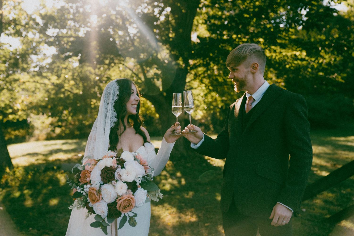 A couple toasts with champagne glasses during their outdoor wedding ceremony.