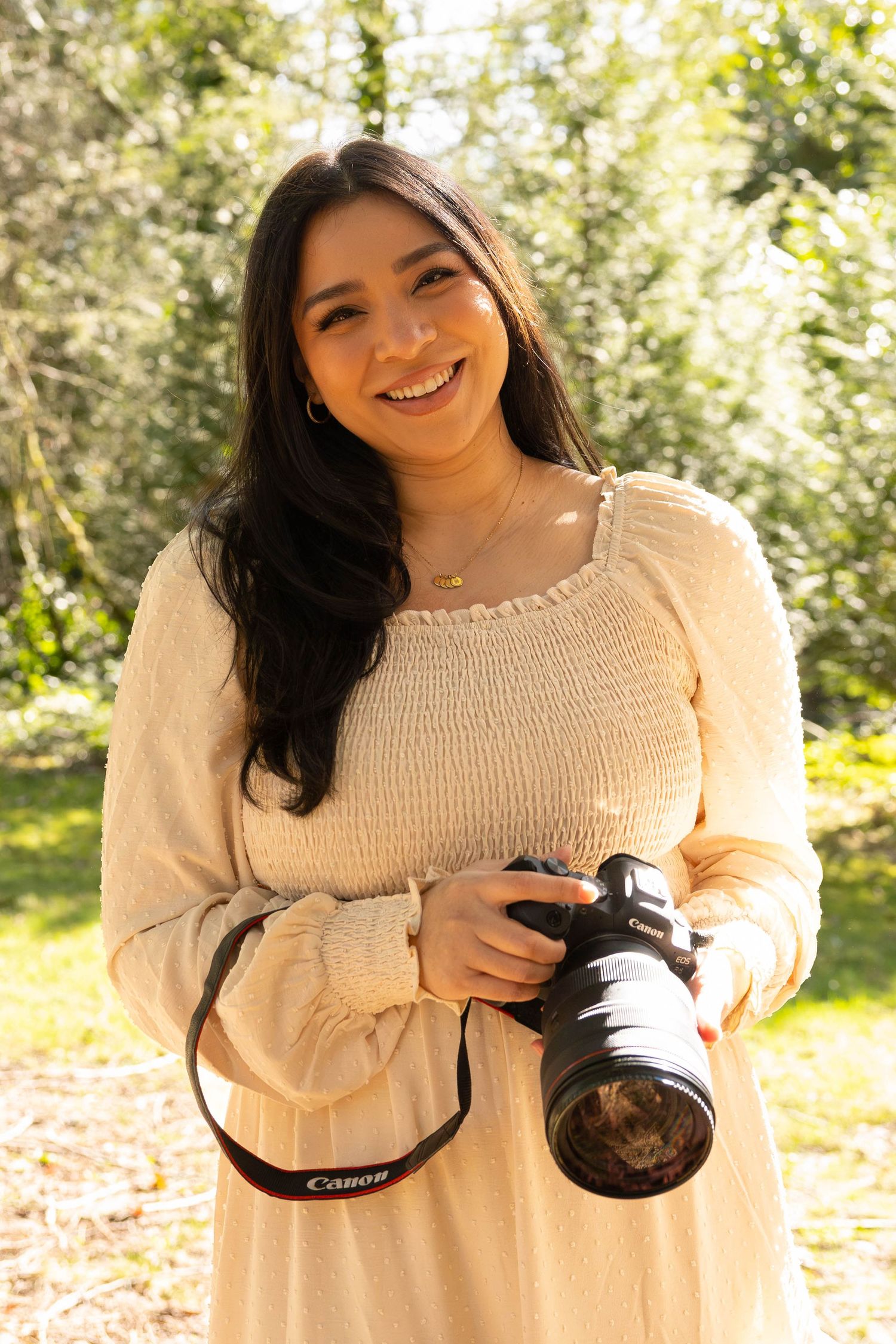 Photography enthusiast in cream sweater holding professional camera outdoors.