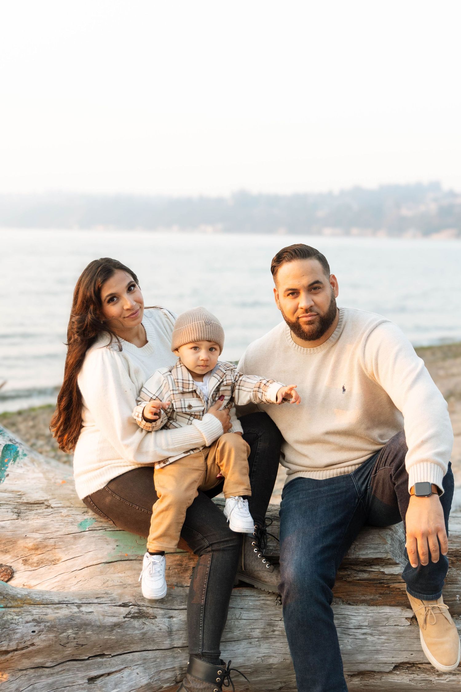 Family sitting together on driftwood at the beach during golden hour.