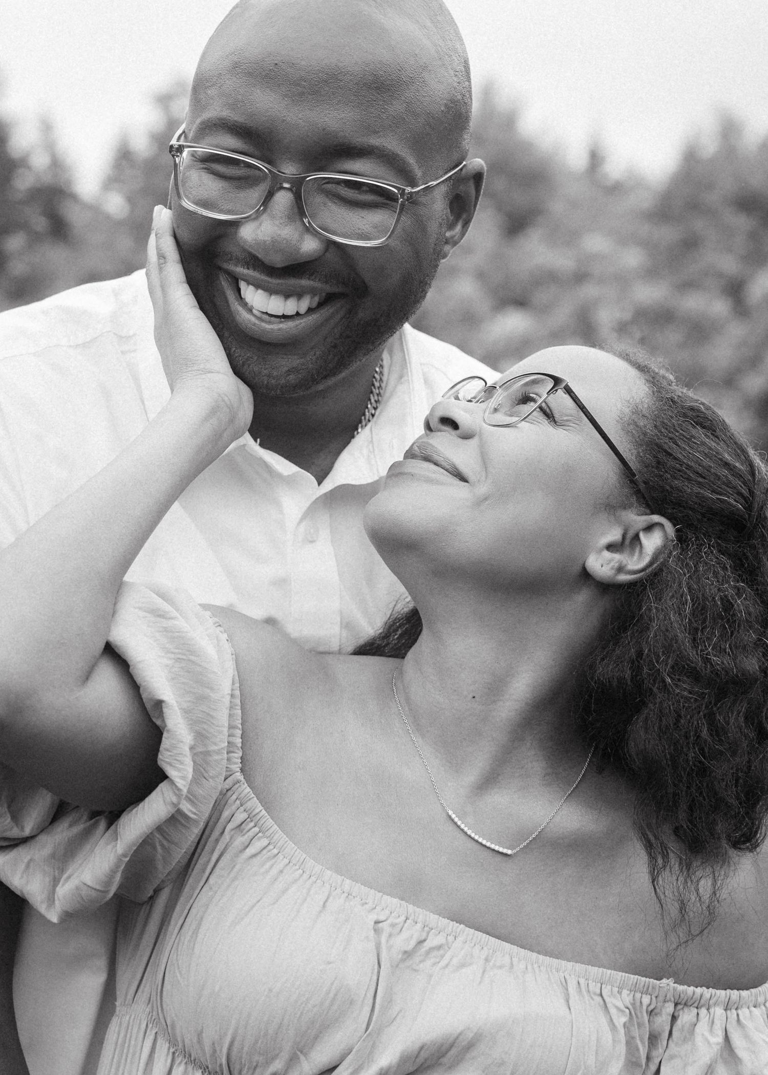 Black and white intimate portrait of a couple sharing a joyful moment outdoors.