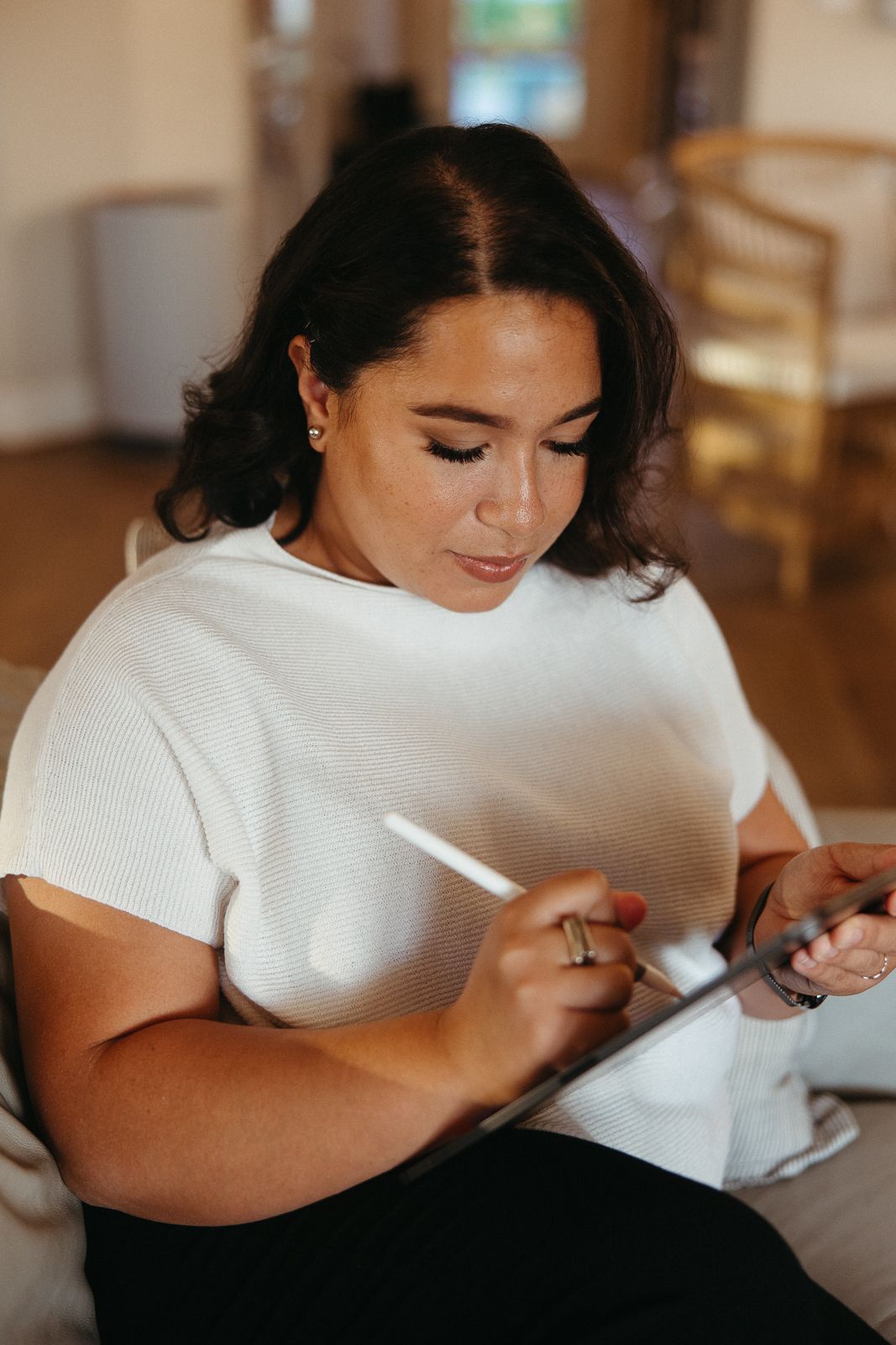 Person in white shirt focused on writing or drawing on a digital tablet indoors.