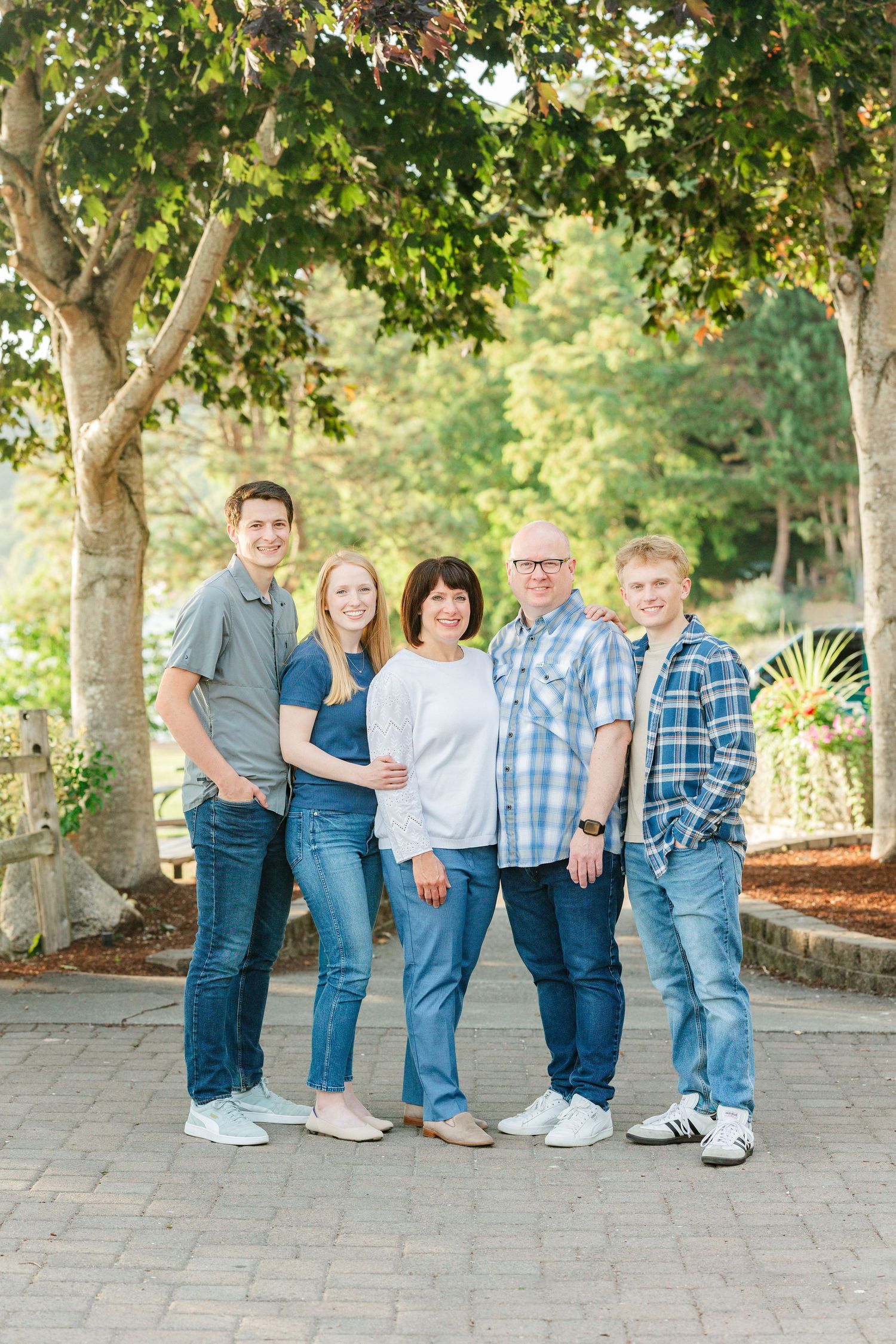 A casual family portrait under trees on a brick patio in warm sunlight.