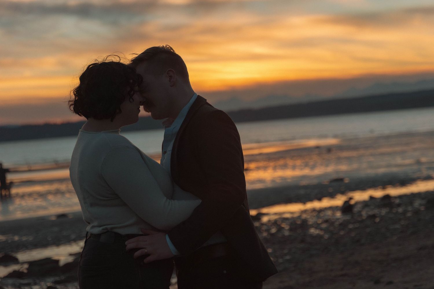 Romantic silhouette of couple sharing an intimate moment during golden sunset on the beach.