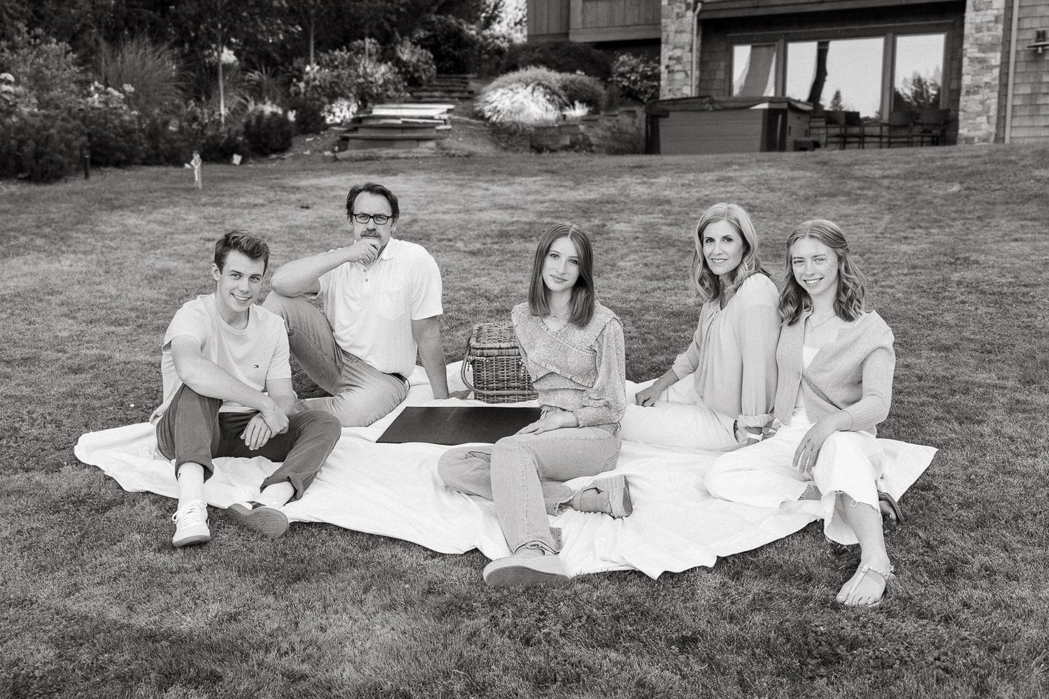 Black and white photo of family group relaxing on blanket on grass.