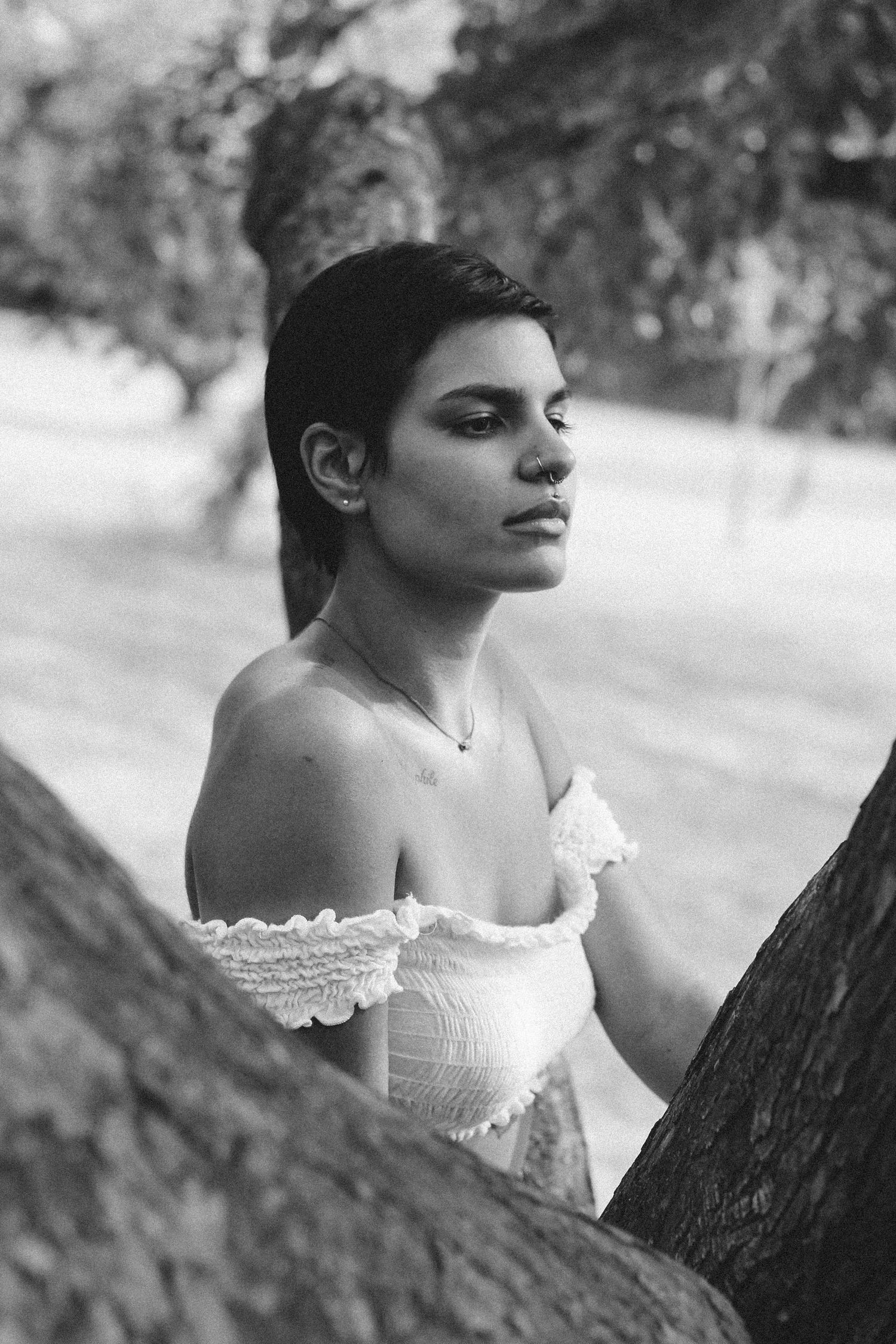 Black and white portrait between trees wearing white lace dress.
