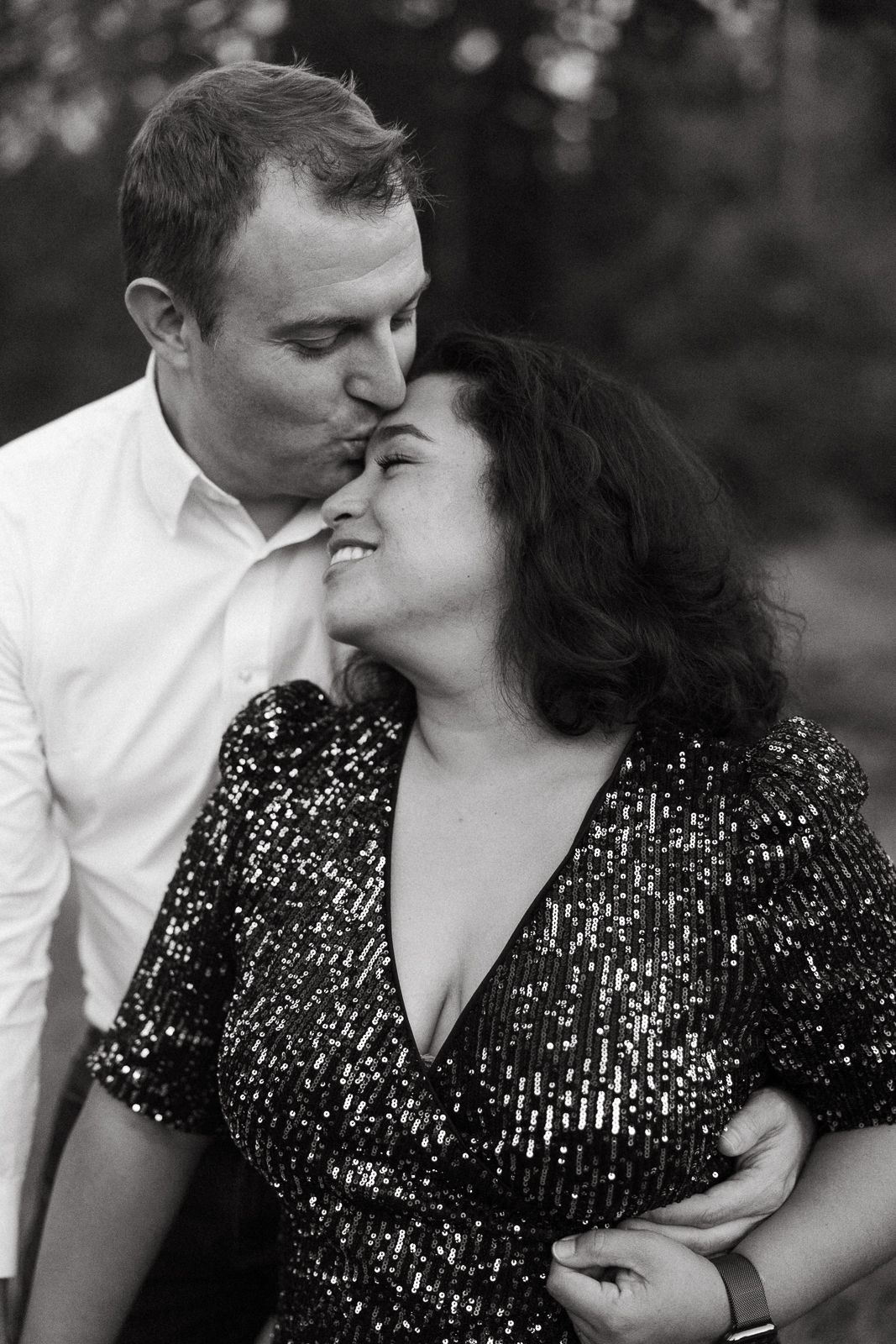 A romantic black and white portrait of a couple embracing with woman wearing a sequined dress.