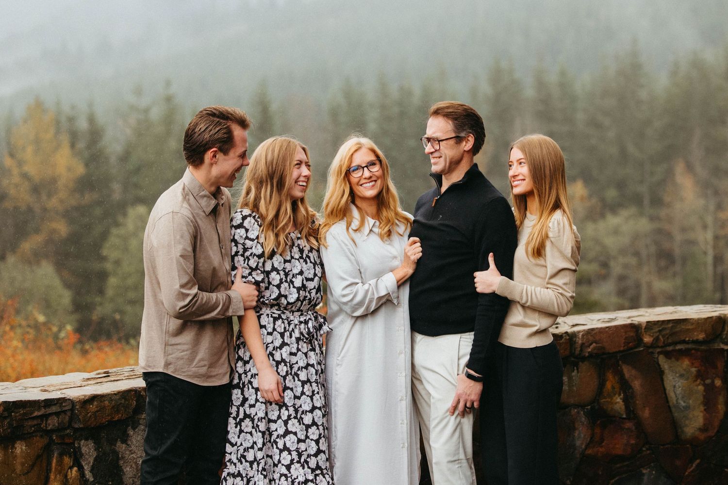 Five people pose together at a scenic mountain overlook during autumn.