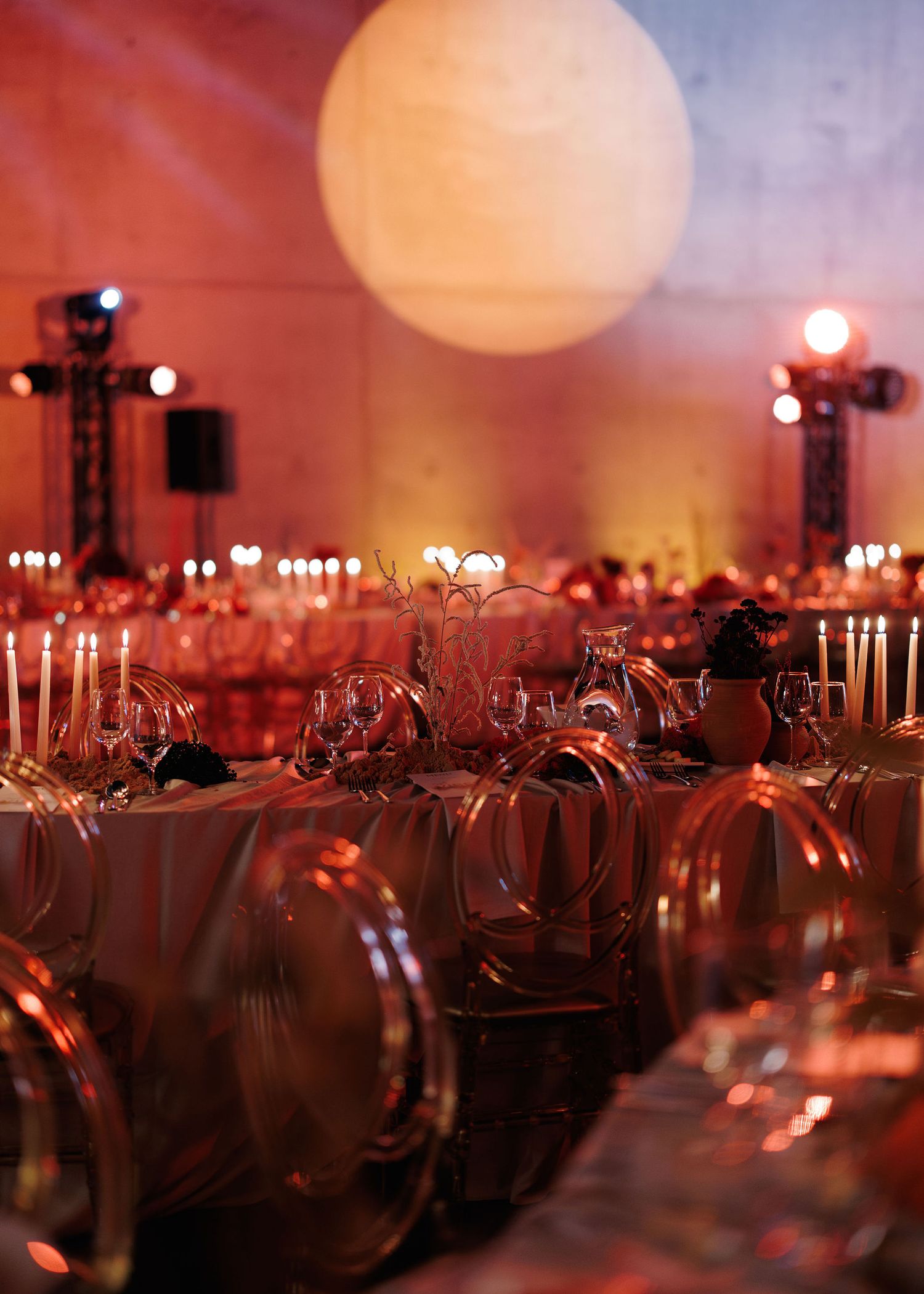 Large illuminated event space with tables and glasses set under dramatic lighting and a glowing orb.