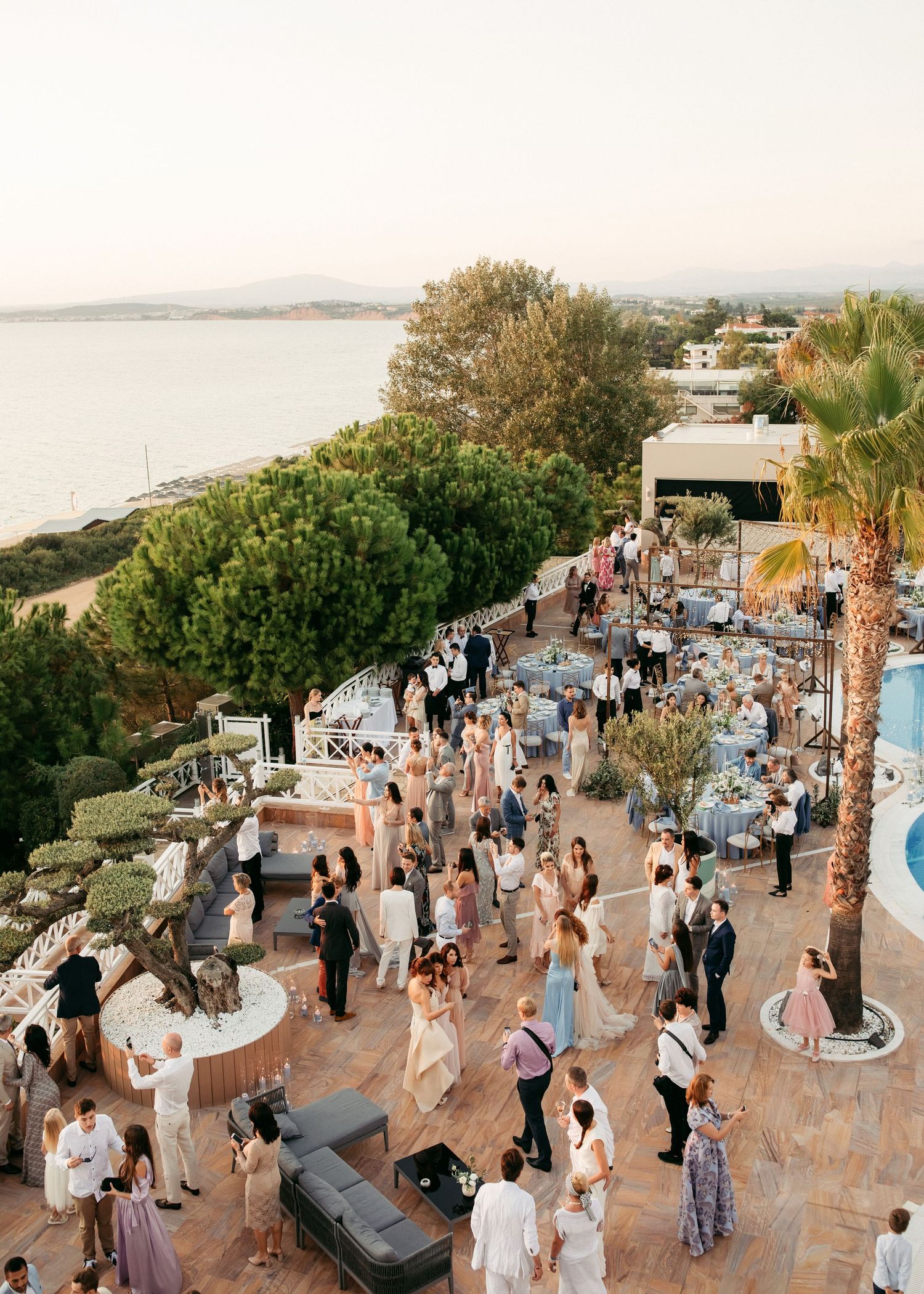 Elegant outdoor wedding reception on a Mediterranean terrace overlooking the sea at golden hour.