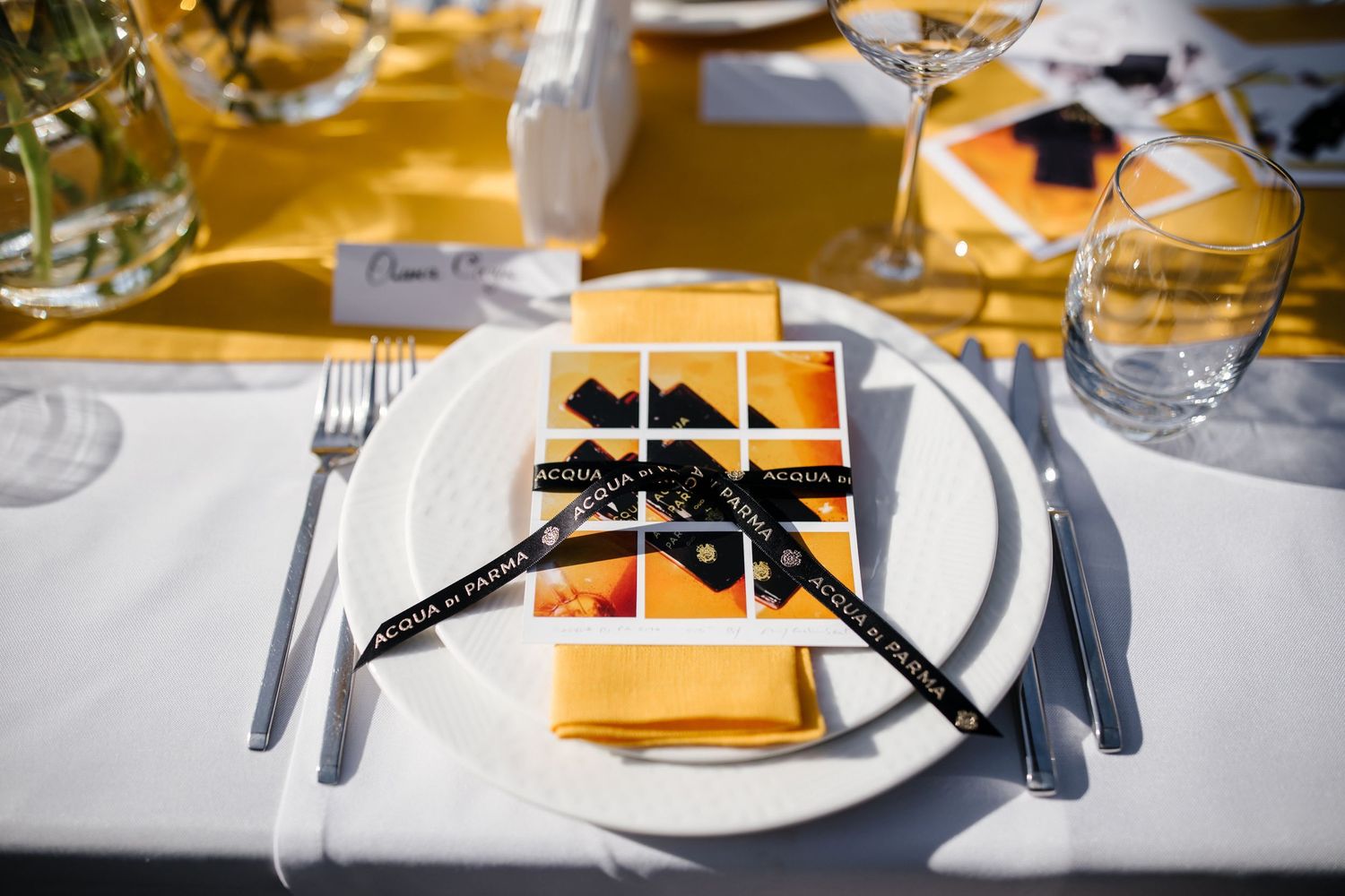 Elegant place setting with yellow napkin and black bow tie decoration on white tablecloth.