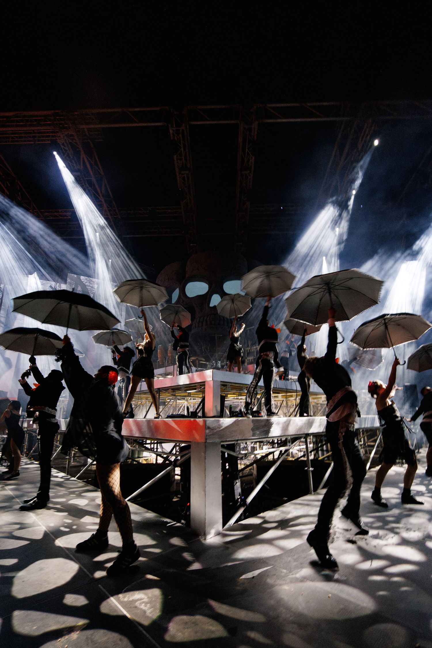 Artistic performance with silhouetted dancers holding umbrellas under dramatic spotlights.
