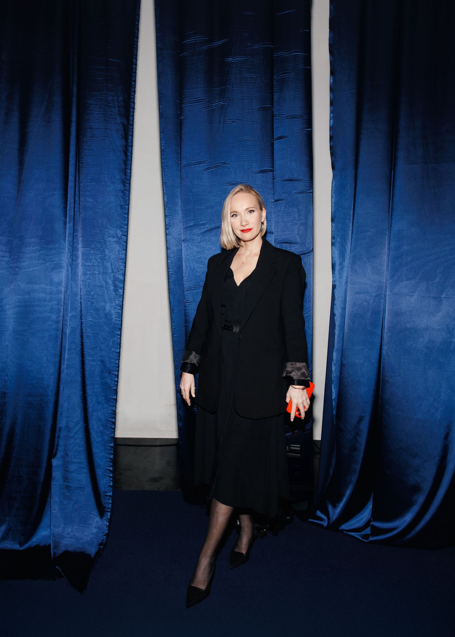 Elegant portrait against blue curtains in a theatrical setting.