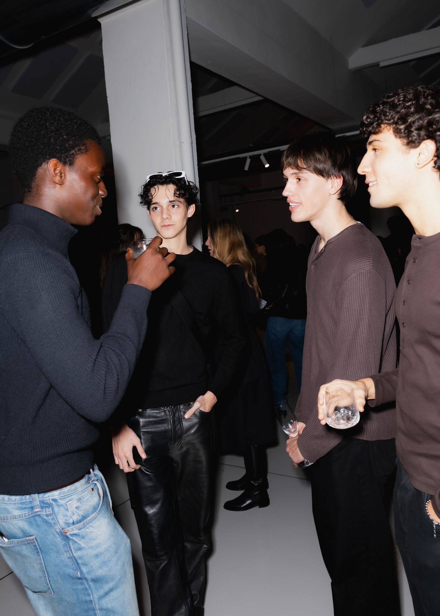 Casual group conversation at a dark indoor event with people wearing casual attire.
