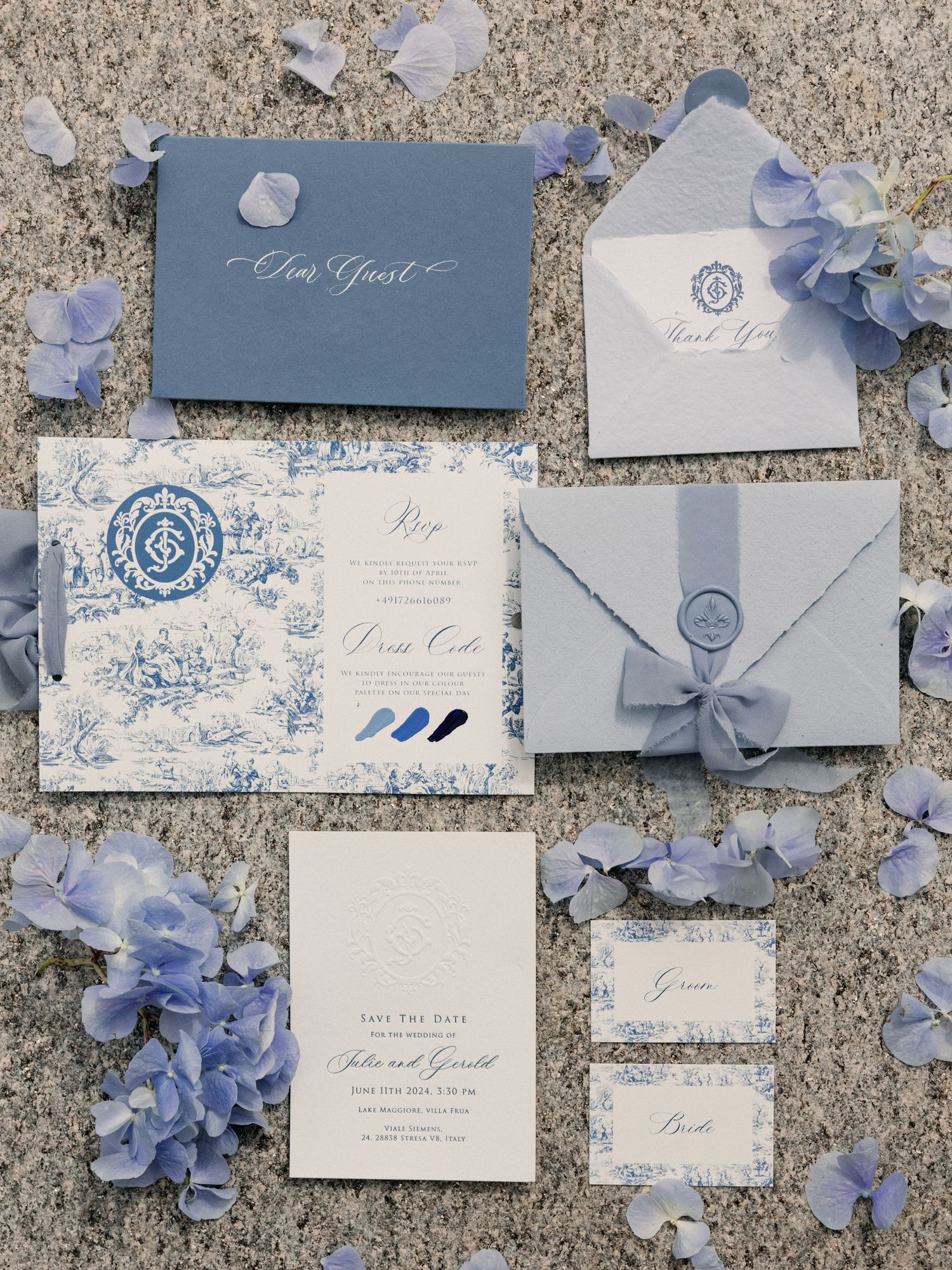 Blue and white wedding invitation suite with floral details and wax seals arranged on textured surface.