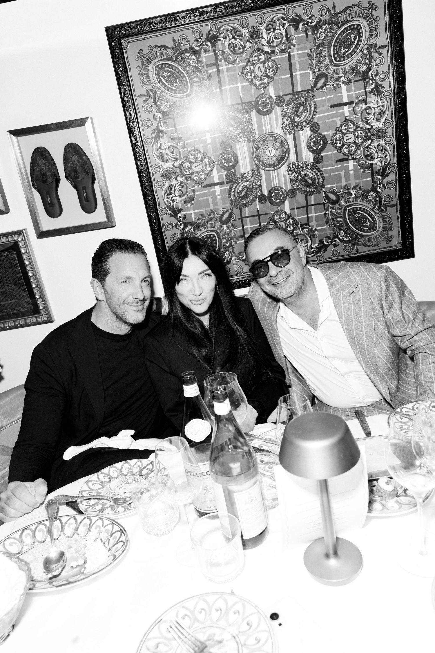 Black and white photo sequence of people dining at a table with decorative artwork on the walls.
