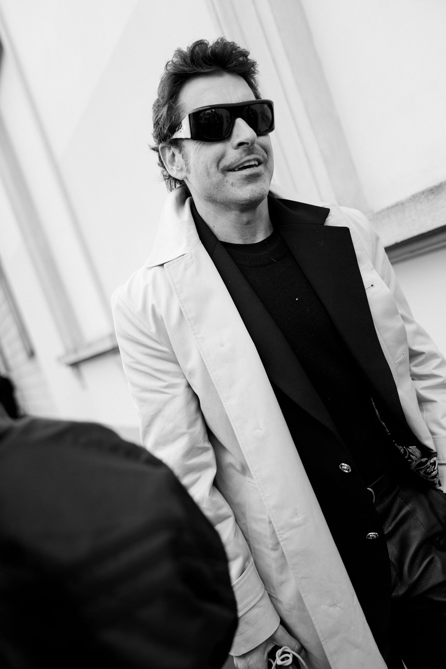 A black and white photo series showing someone in sunglasses and a white jacket from different angles.