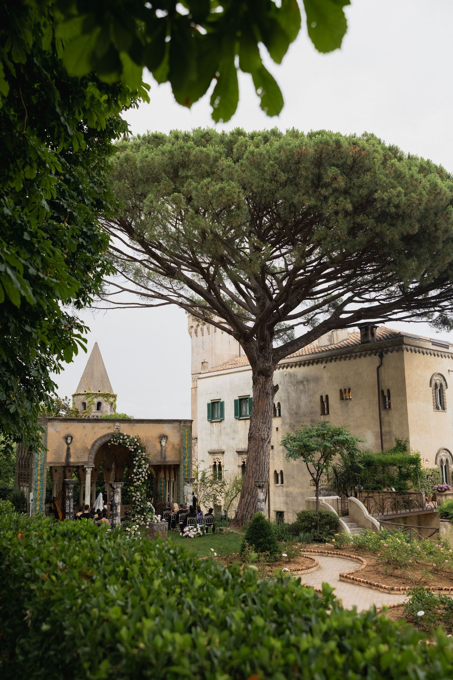 Historic Italian villa with stone tower, lush garden, and umbrella pine tree on the Amalfi Coast.