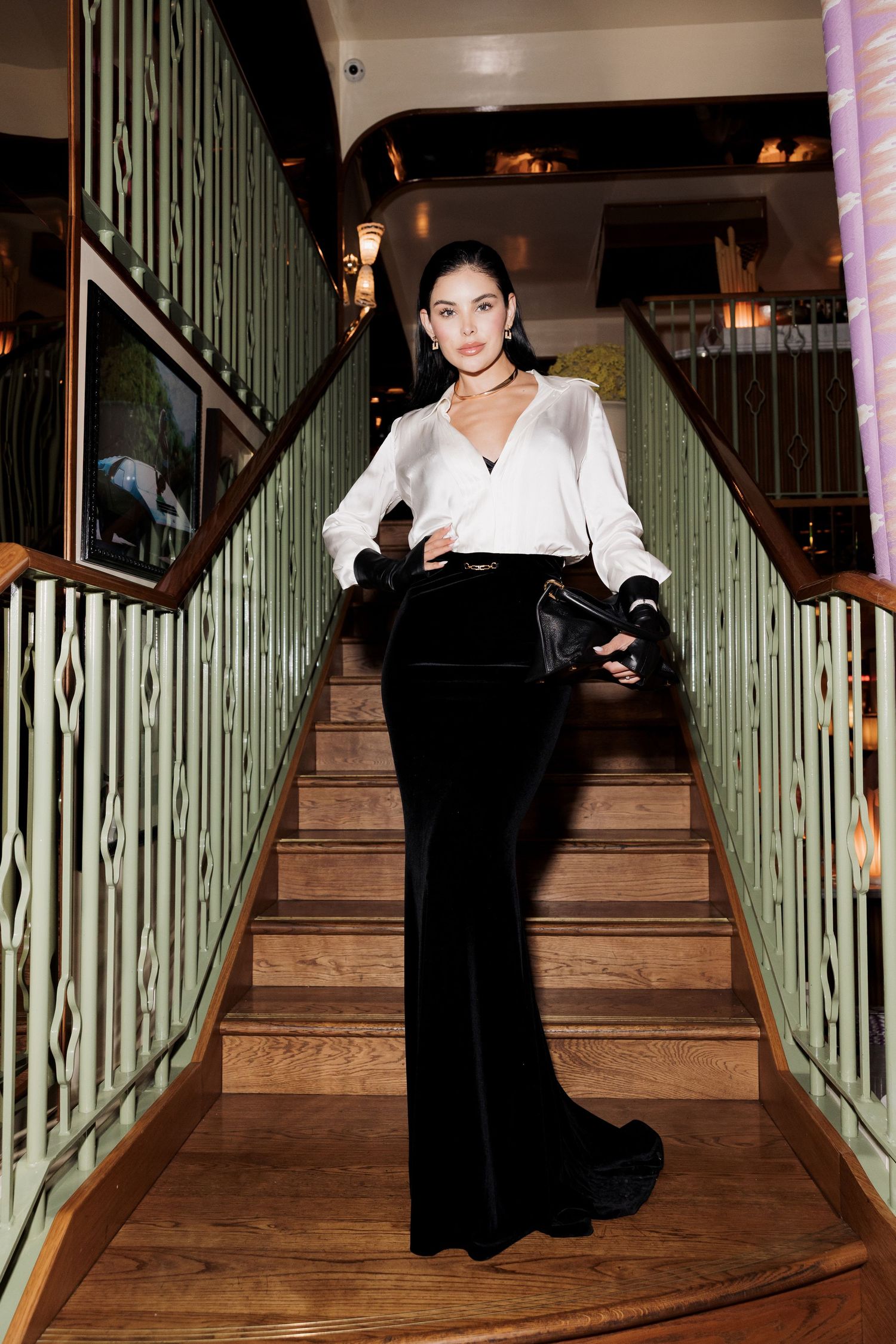 A series of photos showing someone in a white top and dark skirt descending a staircase with green railings.