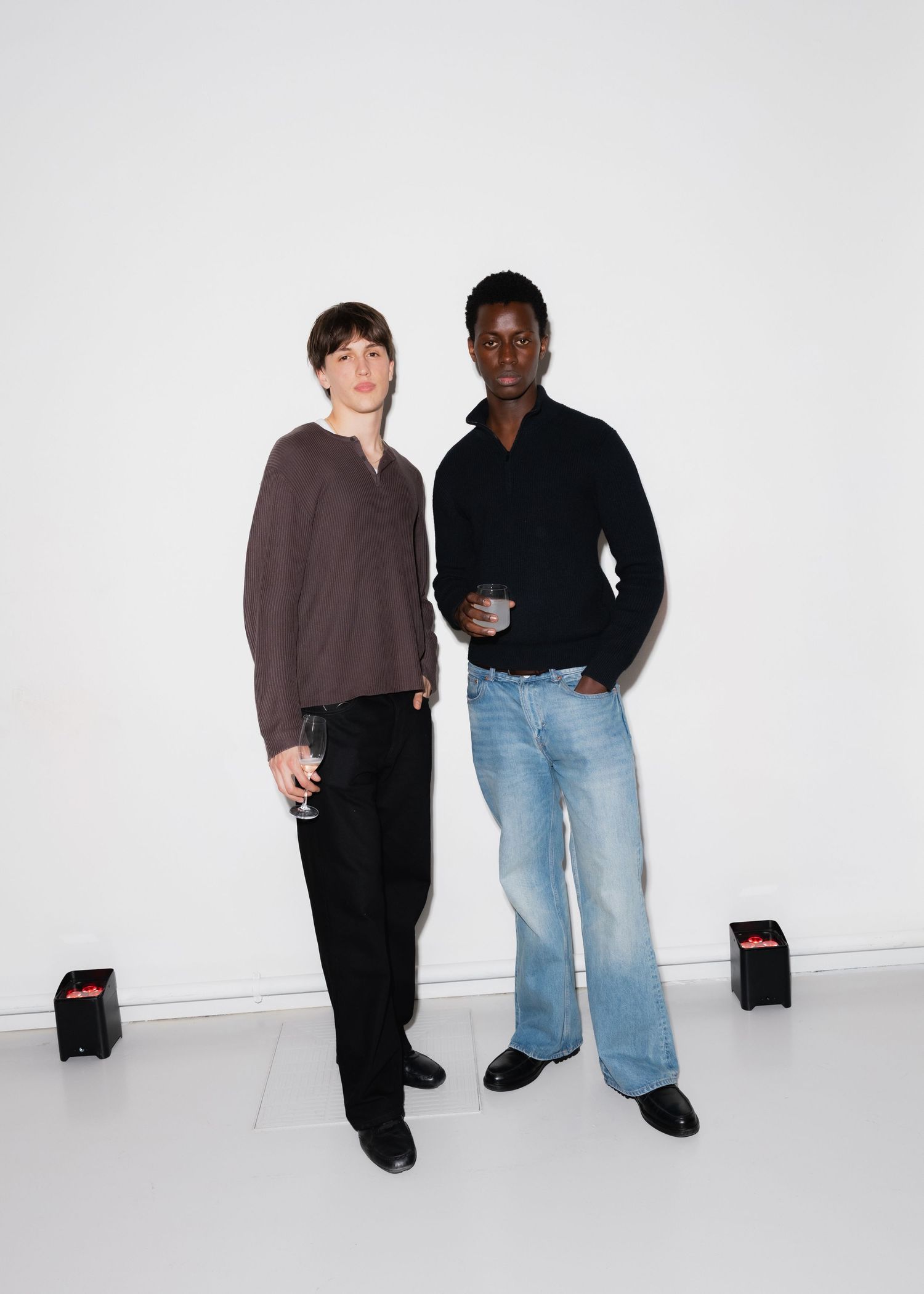Two people pose together against a white backdrop wearing casual attire.