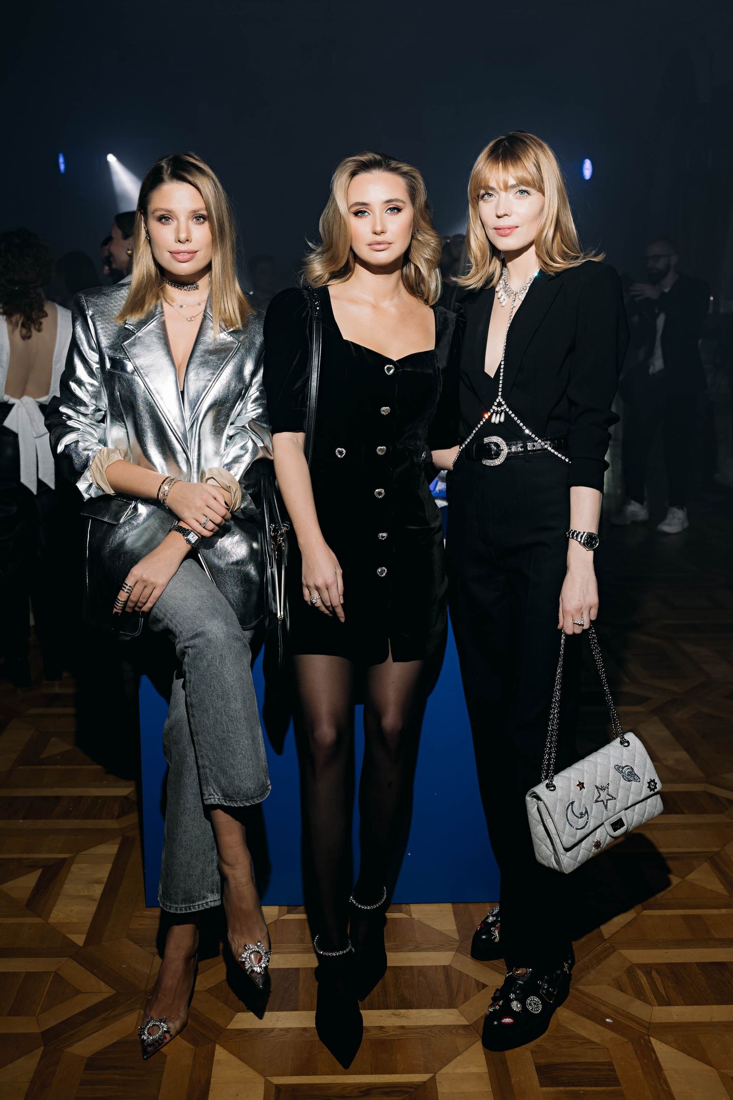 Three people posing in fashionable evening wear at an event.
