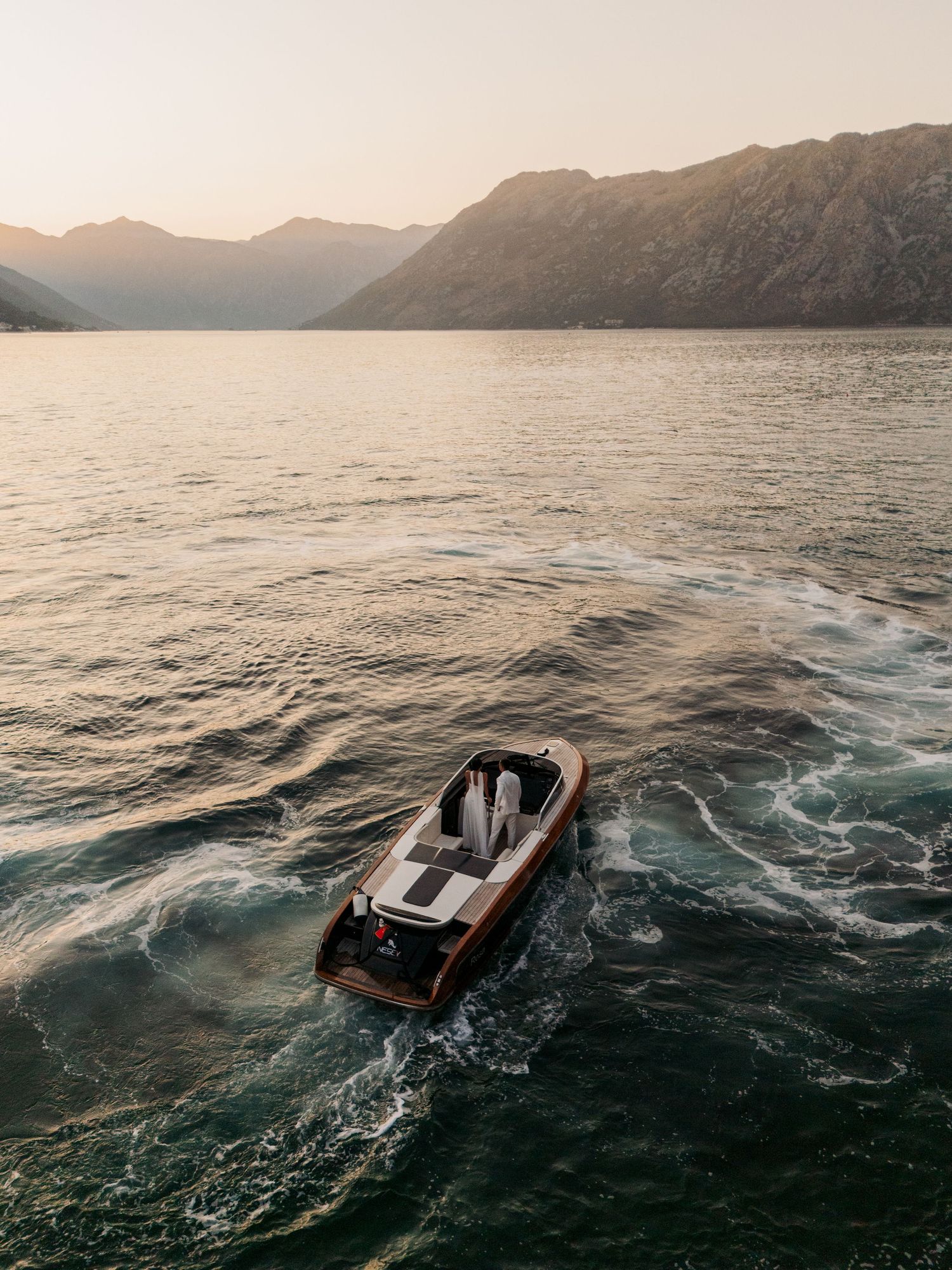 Dramatic sequence of a boat sinking into choppy mountain lake waters at sunset with mountains in the background.