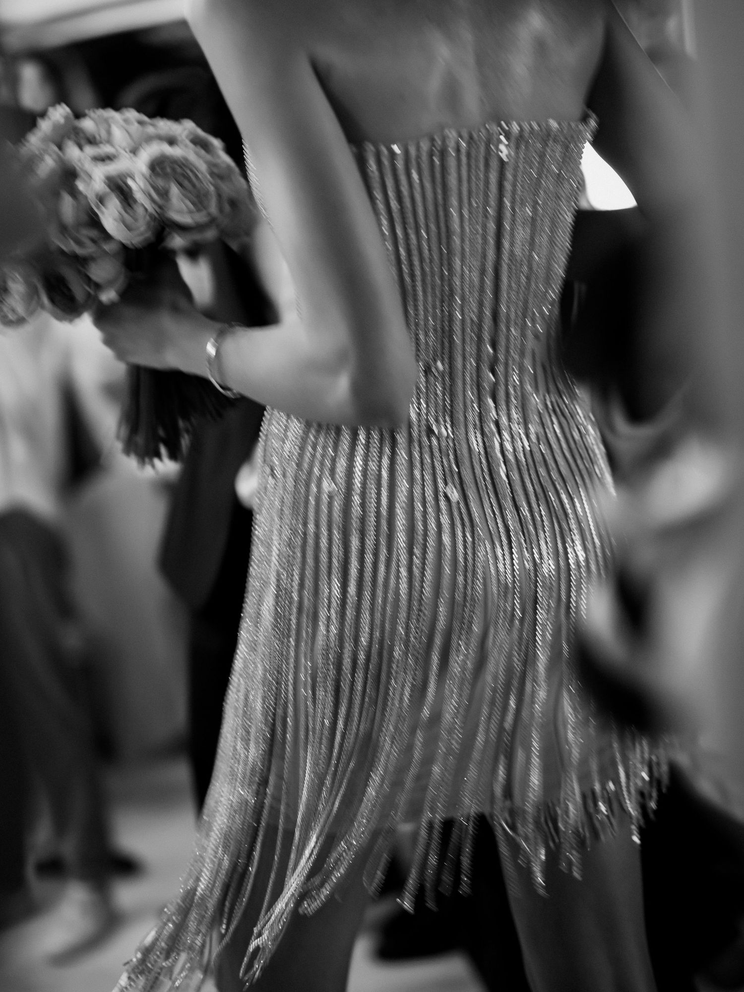 A black and white photo showing the back detail of a beaded dance dress in motion.