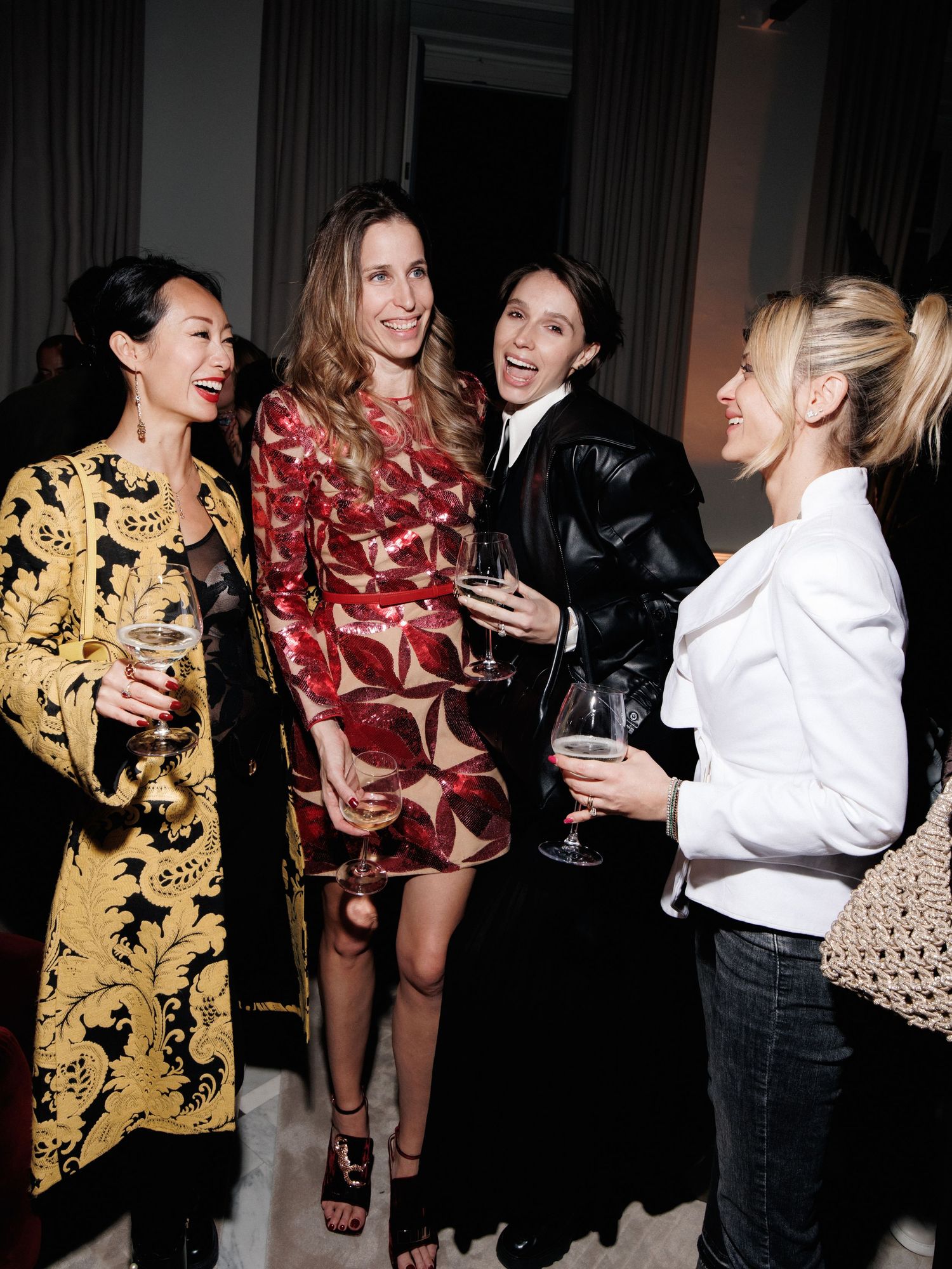 A group of people socializing and laughing at an indoor party wearing red and gold patterned outfits.