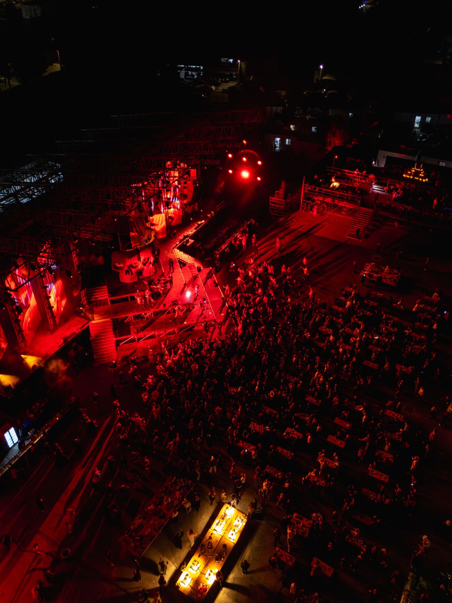 Aerial view of a concert venue illuminated in red lighting with crowd below.
