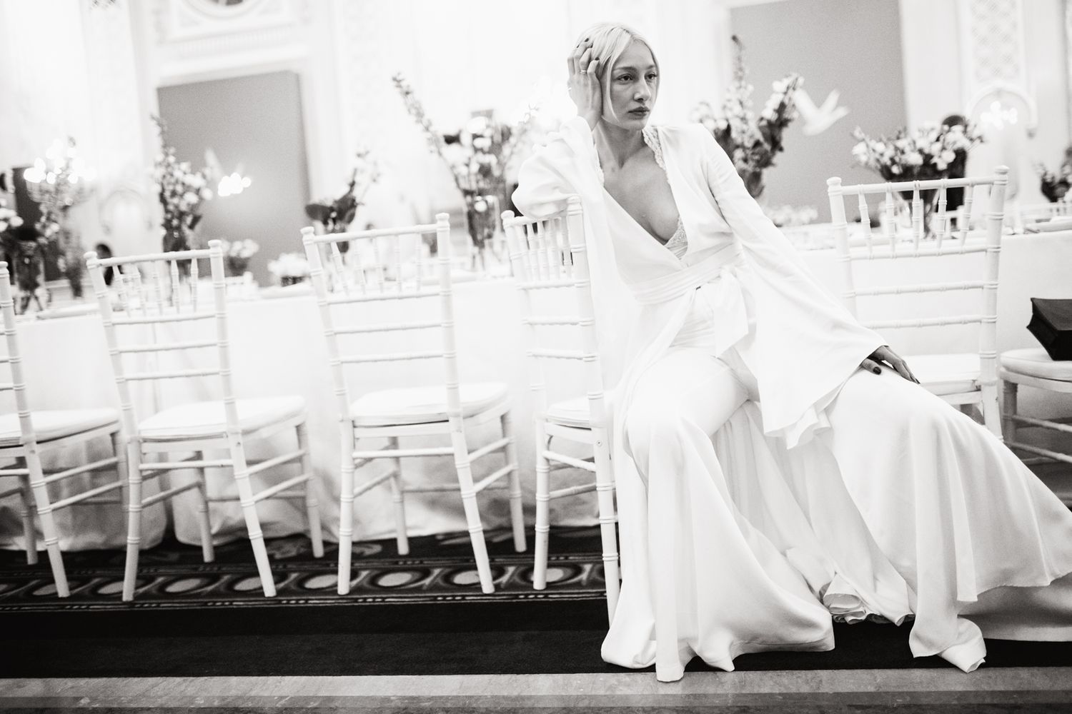 A joyful moment captured in black and white at an elegant wedding reception with white chairs.