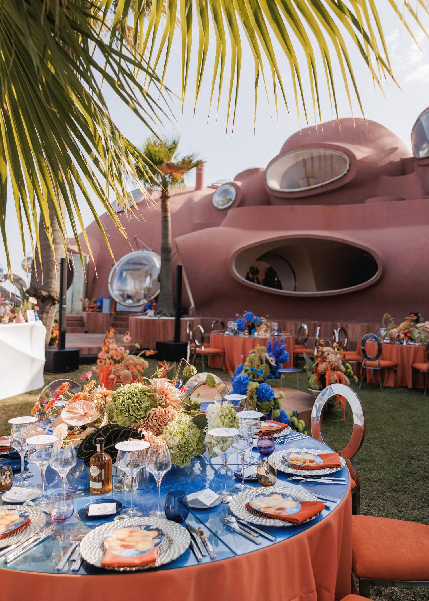 Elegant table setting with blue and coral decor against retro-futuristic building backdrop.
