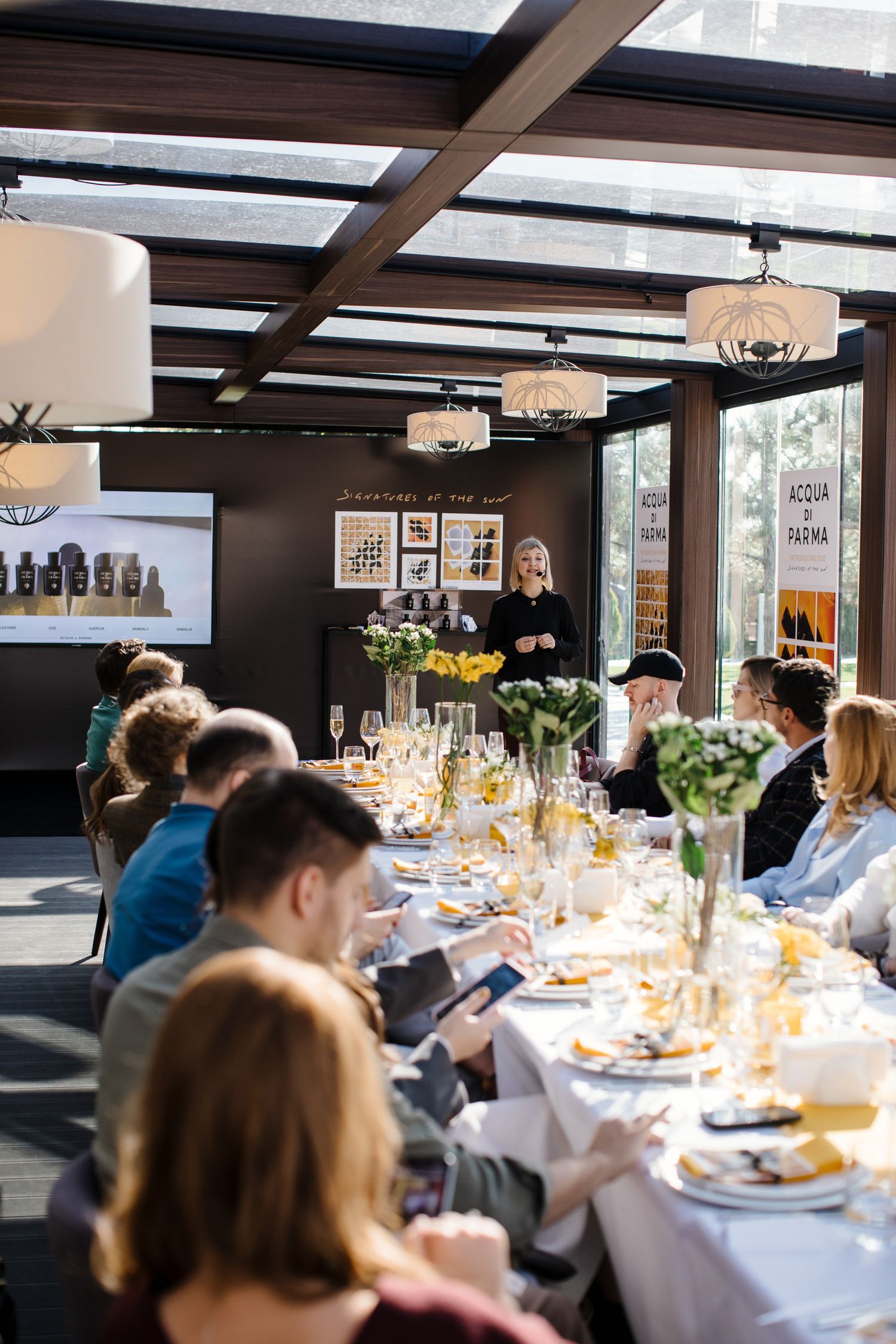 An elegant dining event with guests seated around a long table while being served.