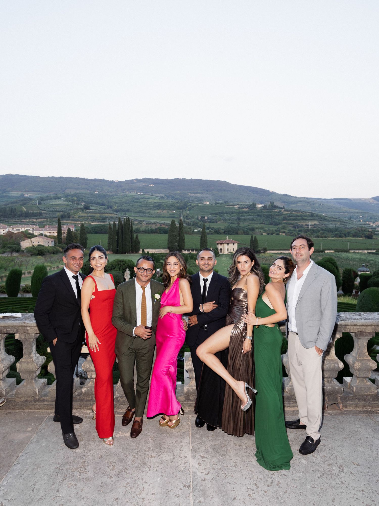 Group photo of wedding guests in formal attire on Italian villa terrace.