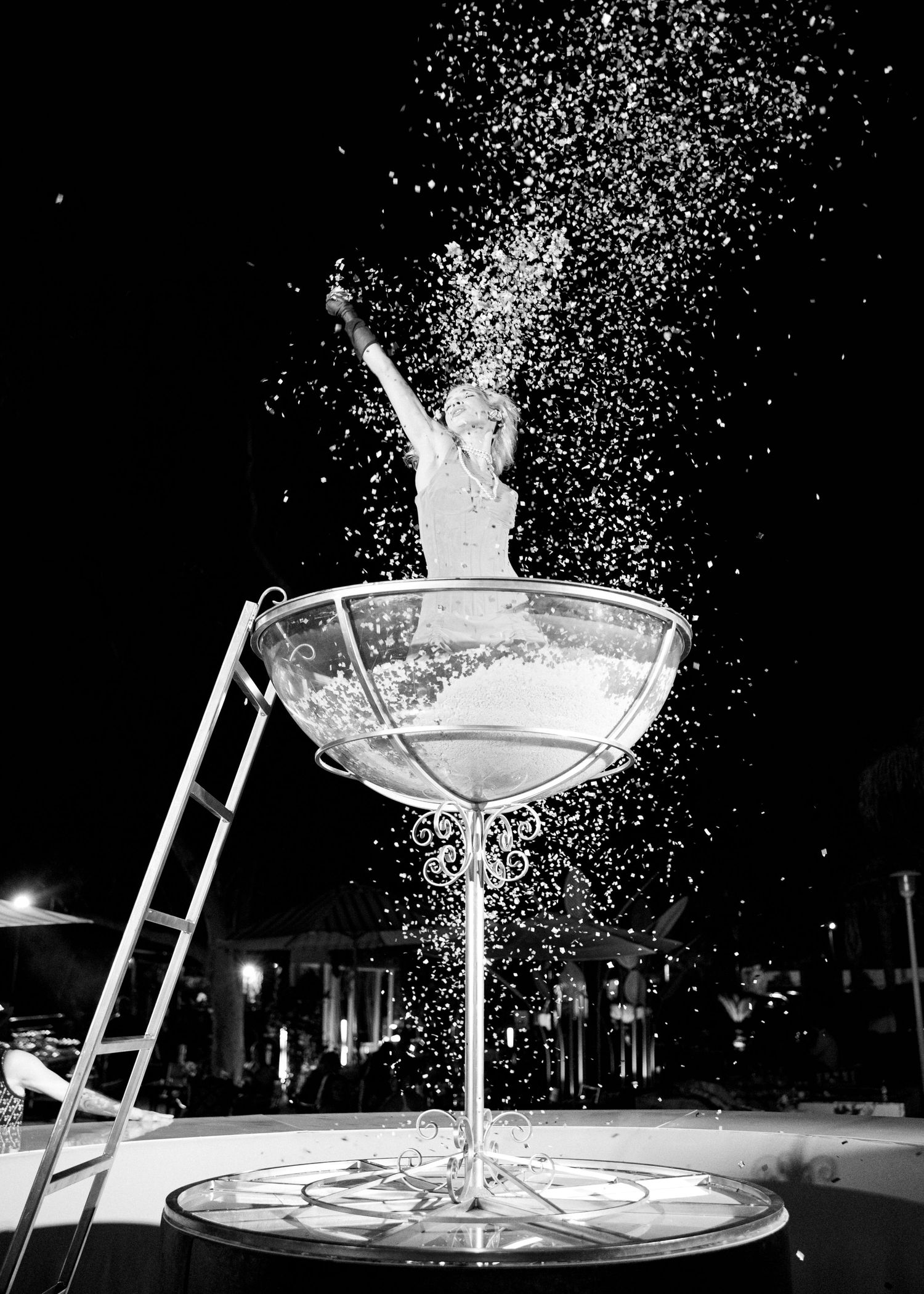 High-speed photography captures liquid splashing from a martini glass in dramatic black and white against dark background.