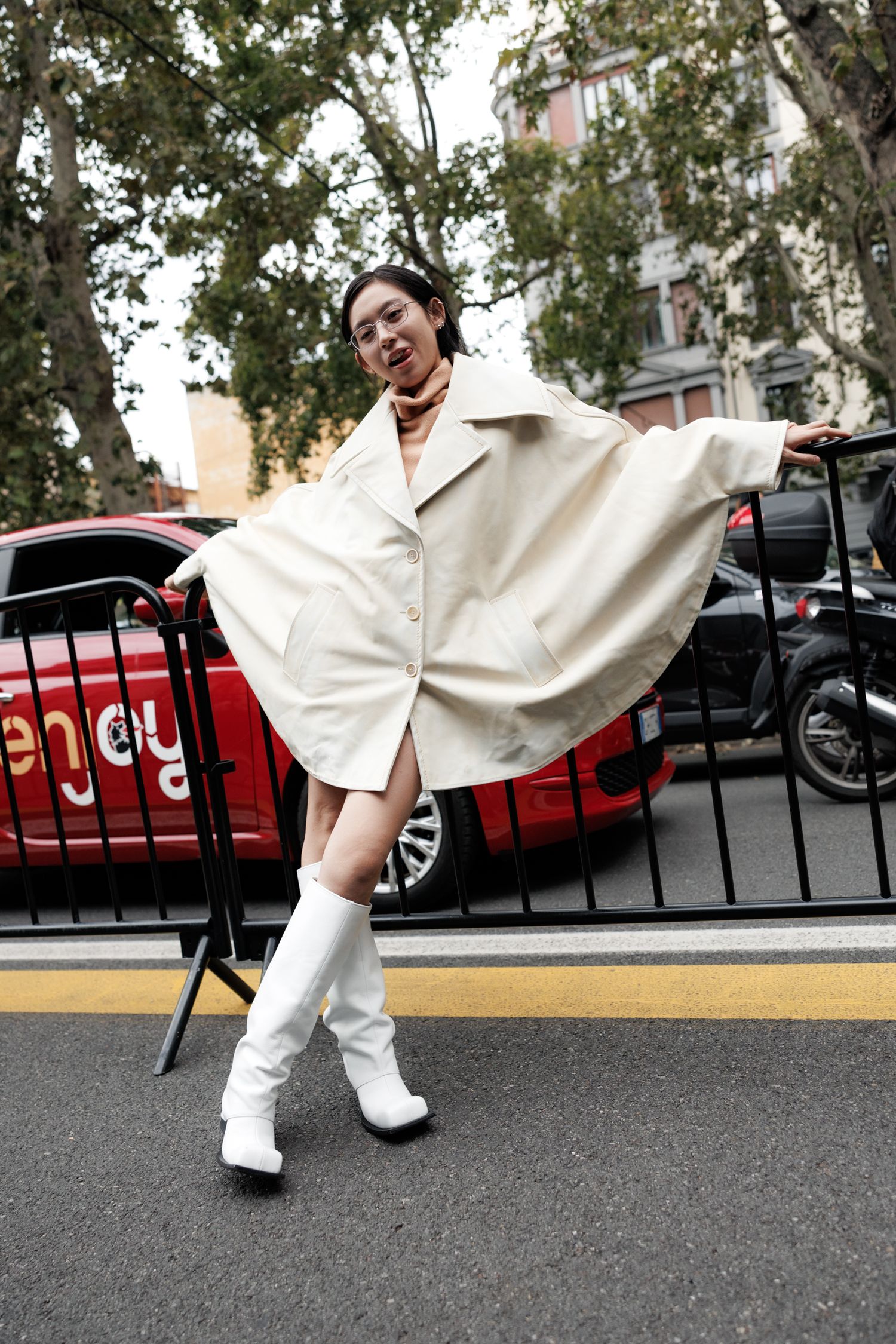 Person in white clothing strikes playful poses in a series of four connected photos on a parking lot.