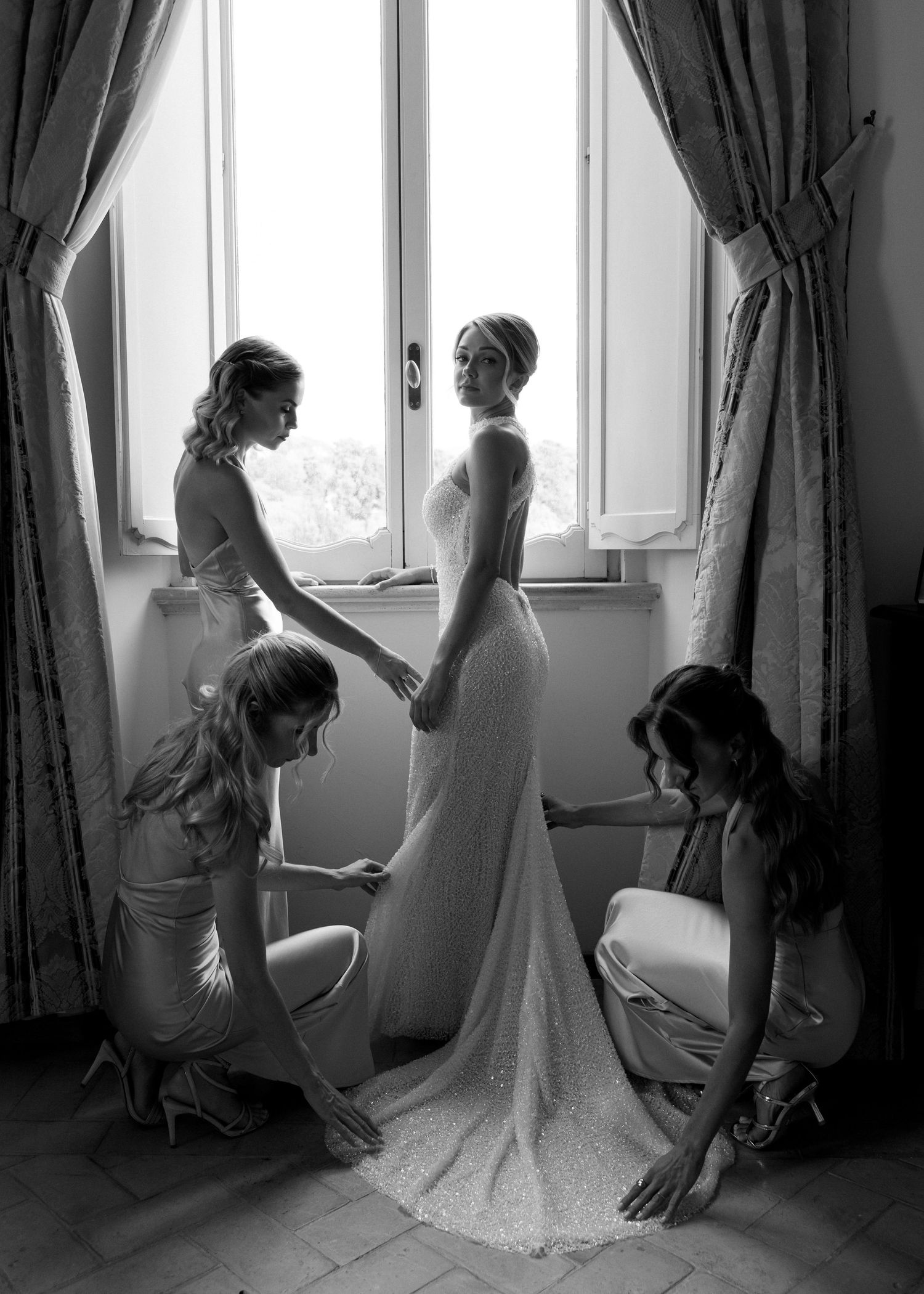 A series of black and white photos showing the process of putting on a wedding dress with lace details.