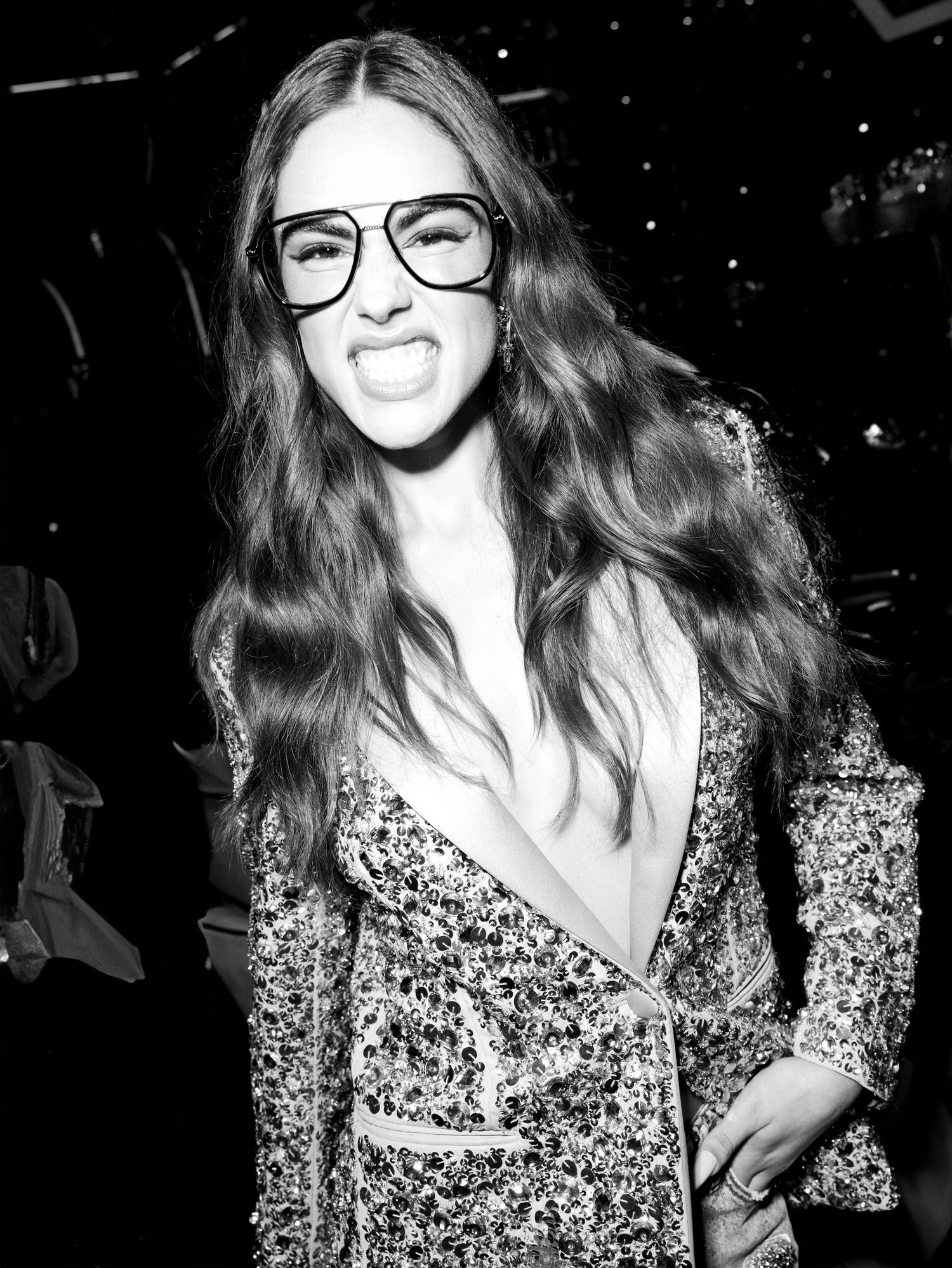 Black and white photo series showing a person with long wavy hair wearing glasses and a floral print dress.