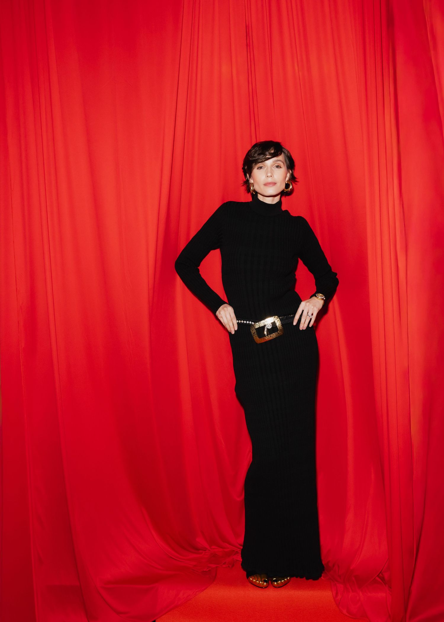 Figure in black dress poses dynamically against vibrant red curtain backdrop in five sequential fashion shots.