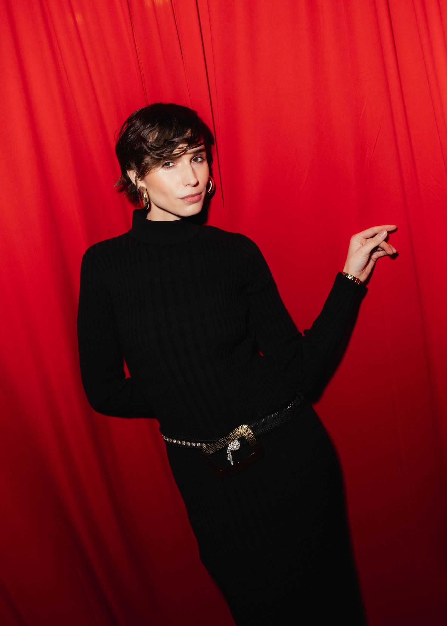 Silhouette poses dramatically against bright red backdrop in fashion photoshoot series.