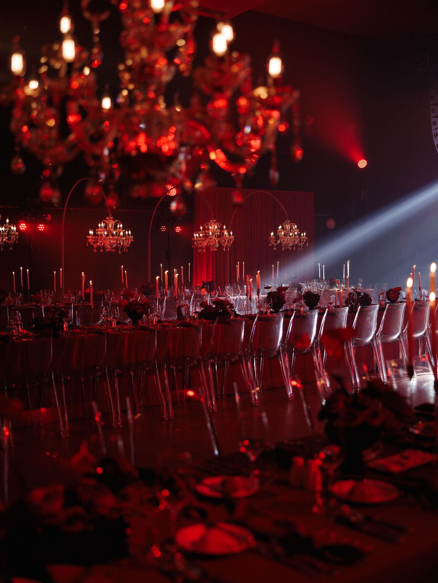 Elegant dining setup with red chandeliers and lighting creating a romantic atmosphere.