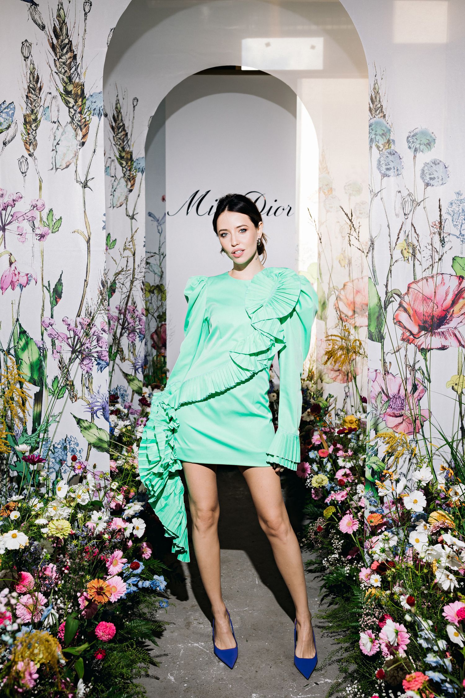Miss Dior fashion display with mint green ruffle dress surrounded by floral archway.