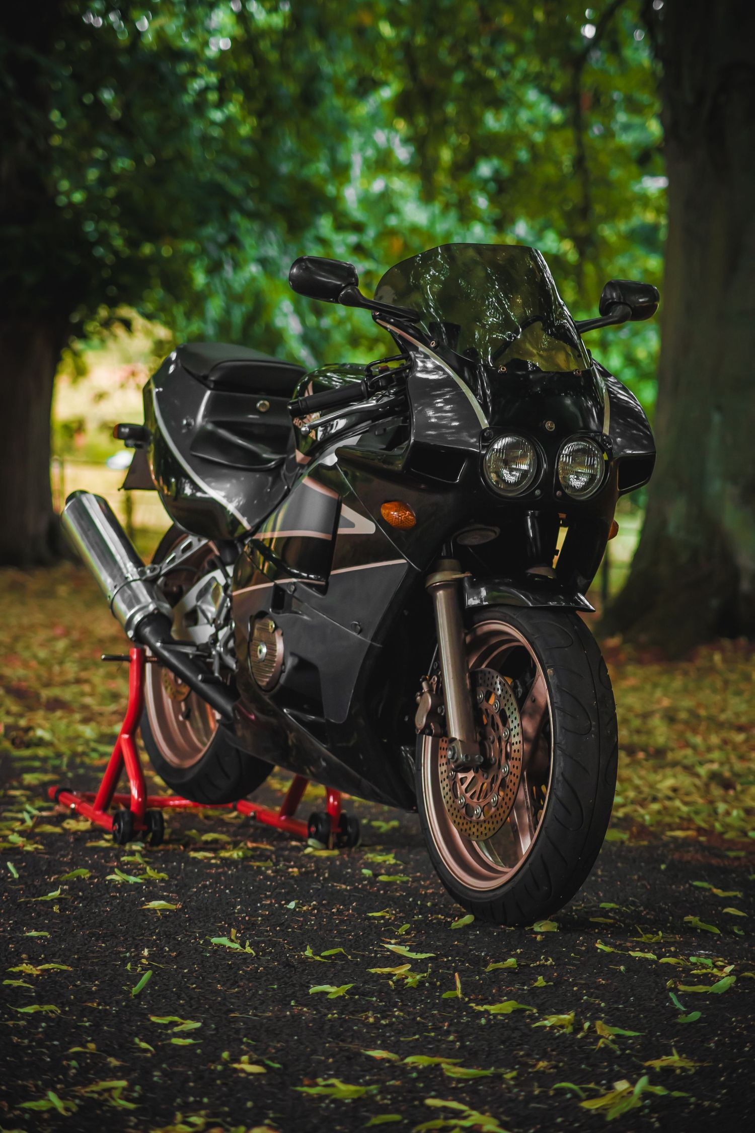Three black sport motorcycles parked in a row on grass with trees in the background.