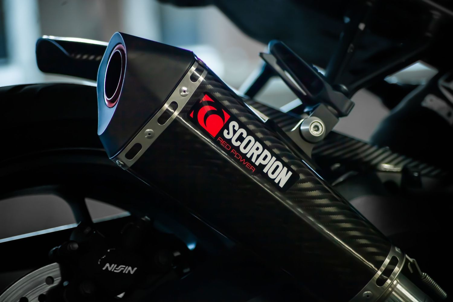 Close-up of a black Scorpion motorcycle exhaust pipe with red logo detail.