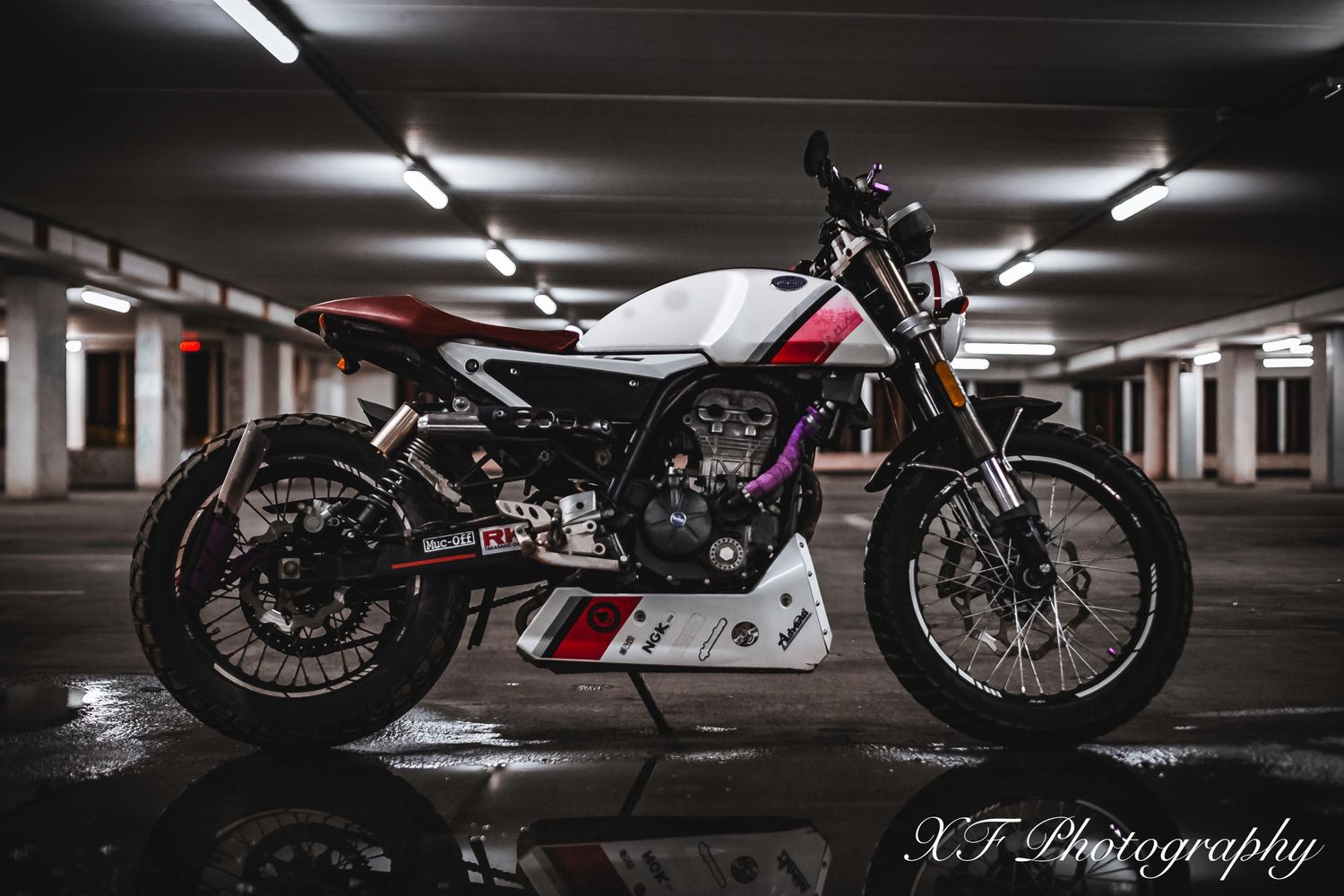 Custom white motorcycle with racing stripes parked in industrial garage setting.