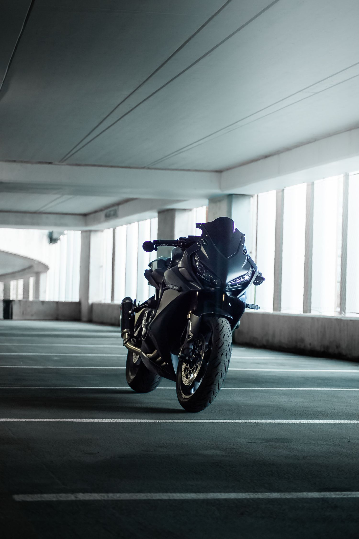 Dark silhouette of a motorcycle in a dimly lit parking garage with dramatic lighting and shadows.