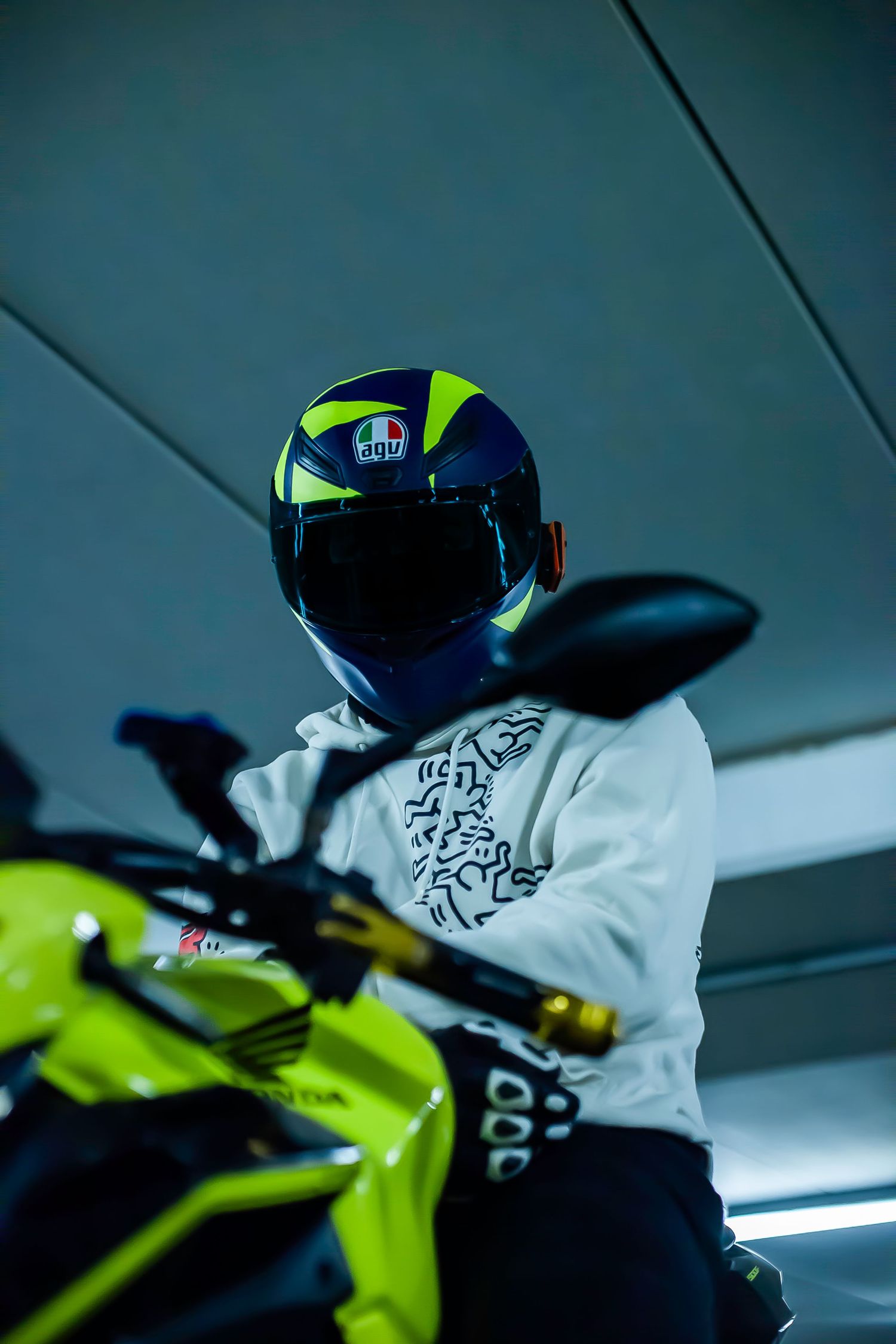 Neon yellow sport bike with racing helmet in dim garage lighting.