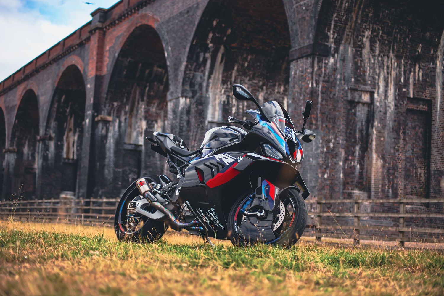 A black motorcycle parked in front of a rustic brick building with arched windows and weathered architecture.