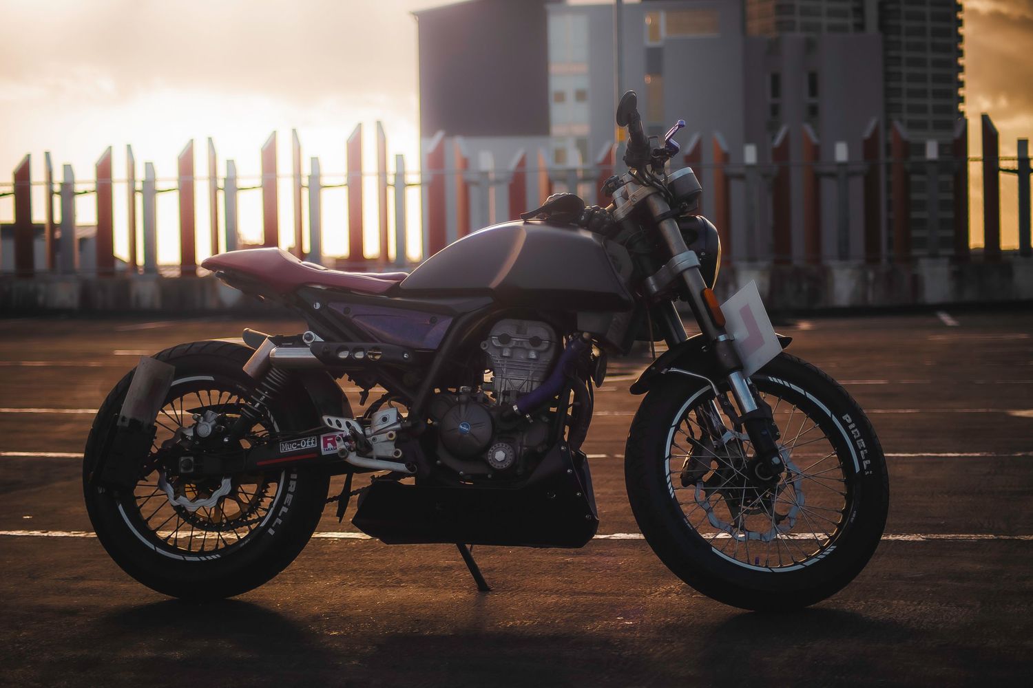 Custom motorcycle parked on a street at sunset with warm golden lighting casting long shadows.