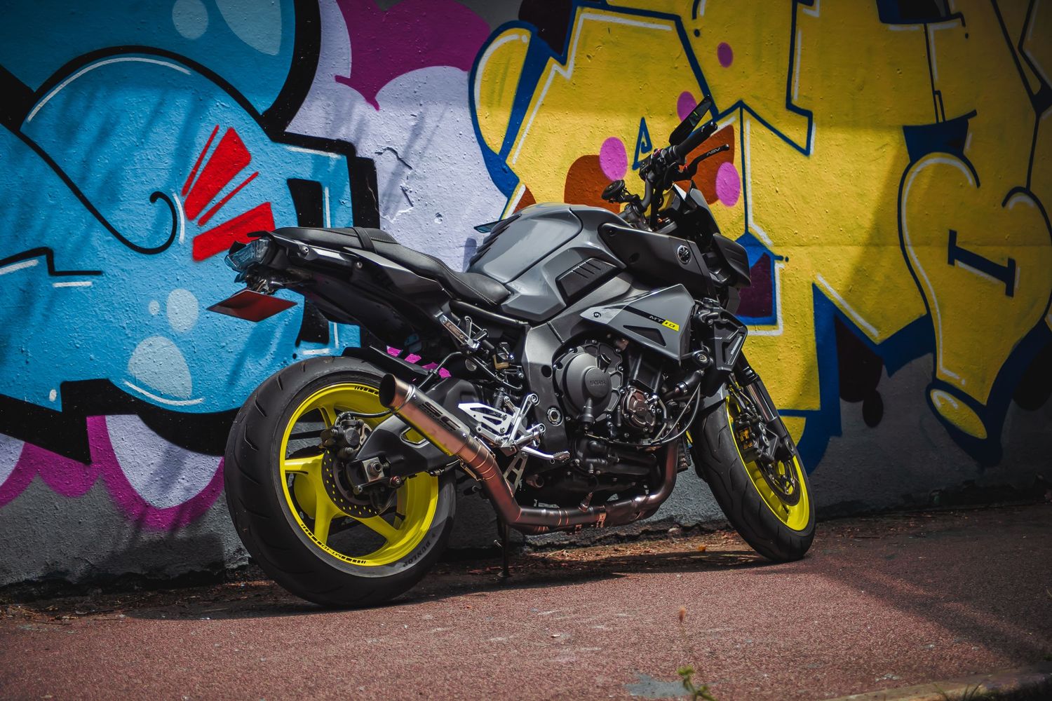 Sport motorcycle parked against colorful graffiti wall with yellow accents.
