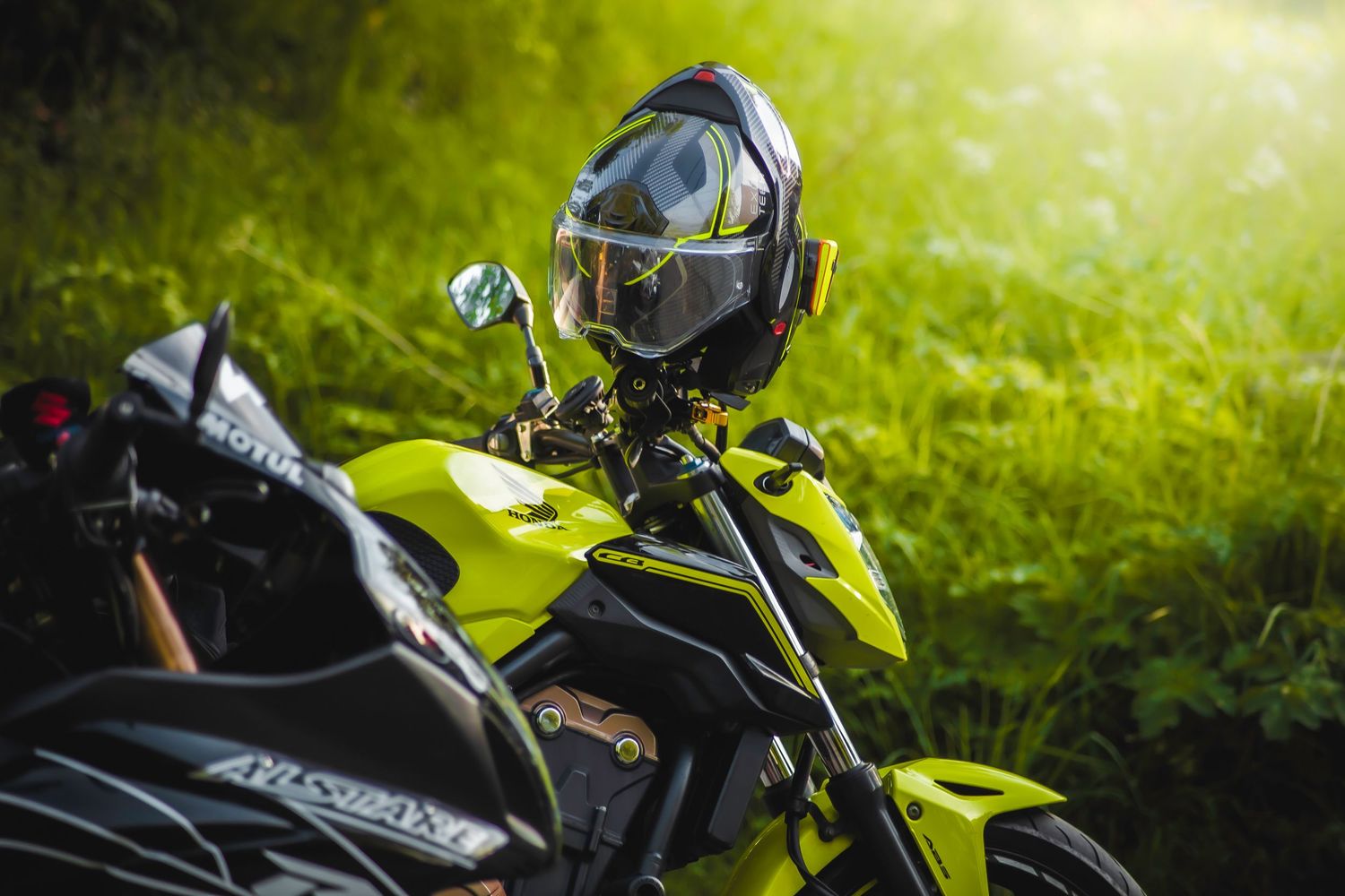 A neon yellow motorcycle with black accents parked in front of green foliage with a helmet resting on the handlebars.